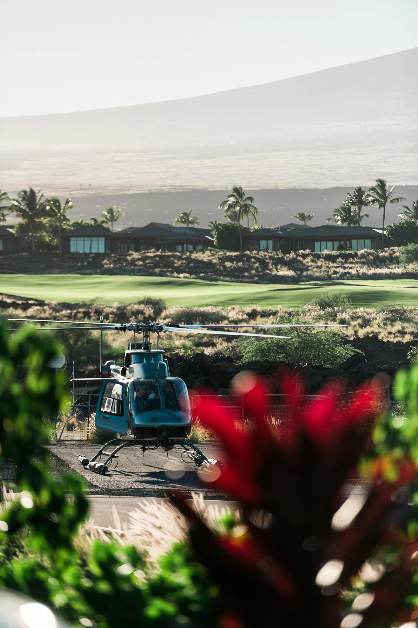 Helicopter on the ground with a golf course in the background and lush plants in the foreground