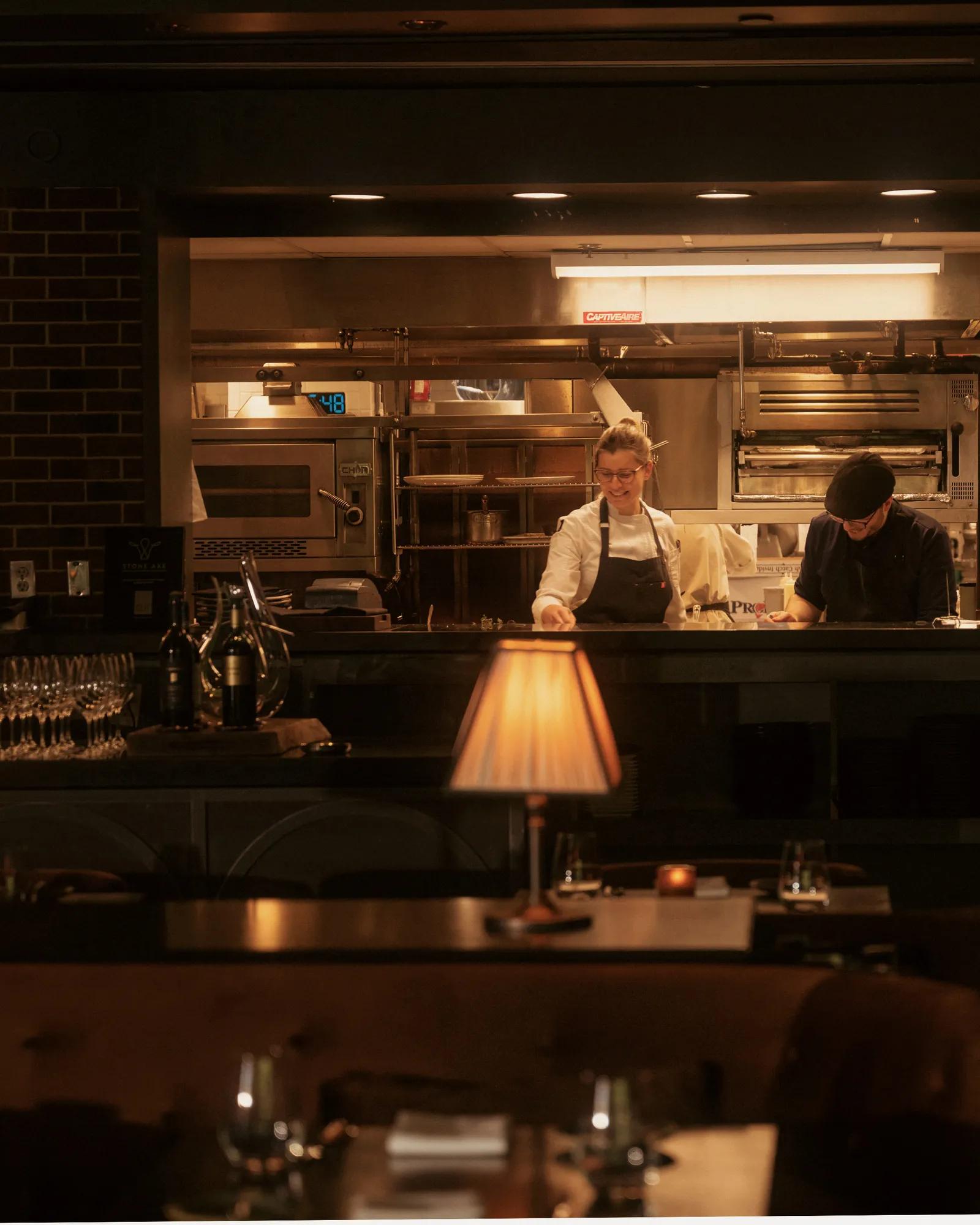 Culinary team in an open kitchen with tables and lamps in the foreground