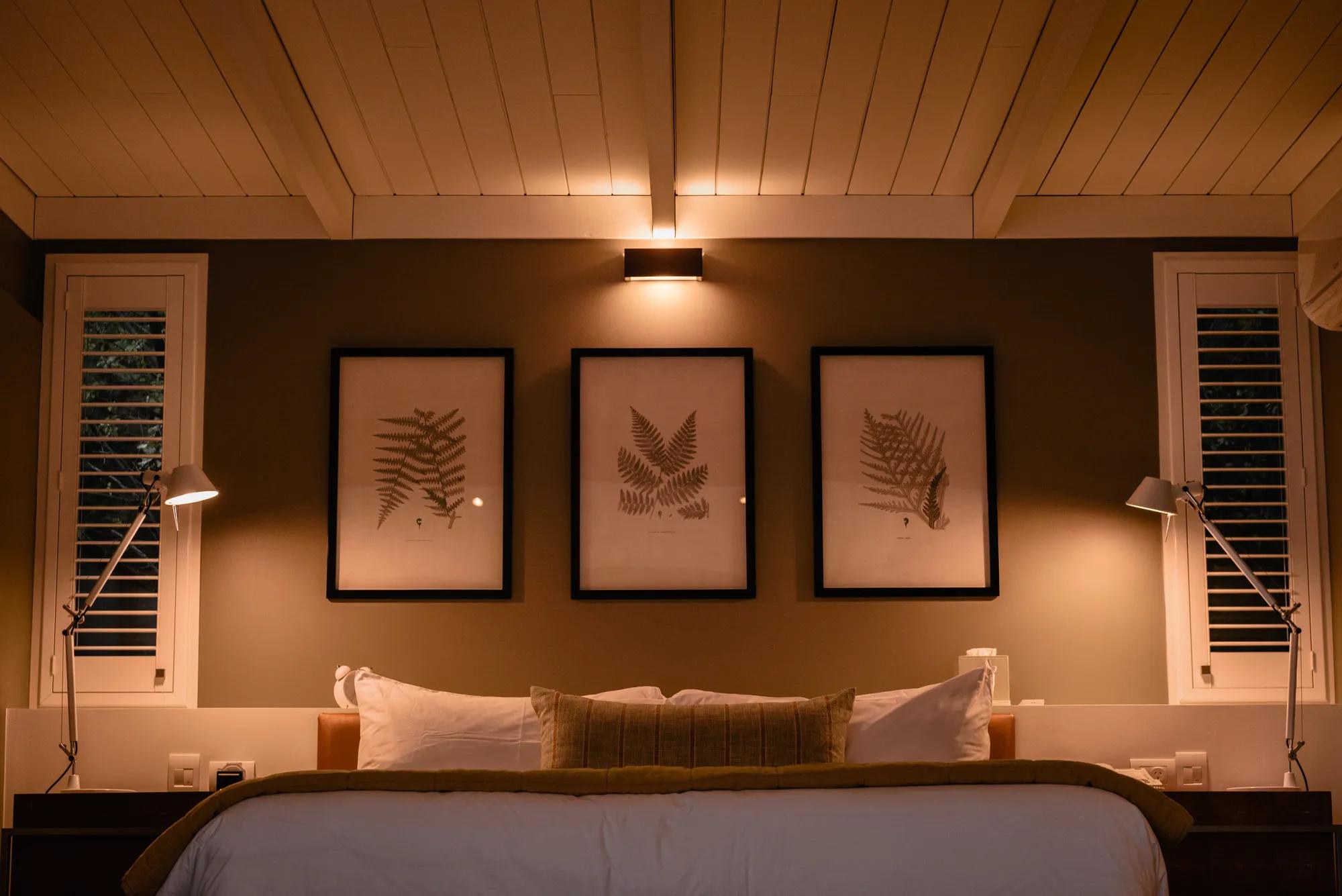 Luxury hotel bedroom at night with turndown service, plush white bedding, warm mood lighting, and a cosy, relaxing ambiance. 