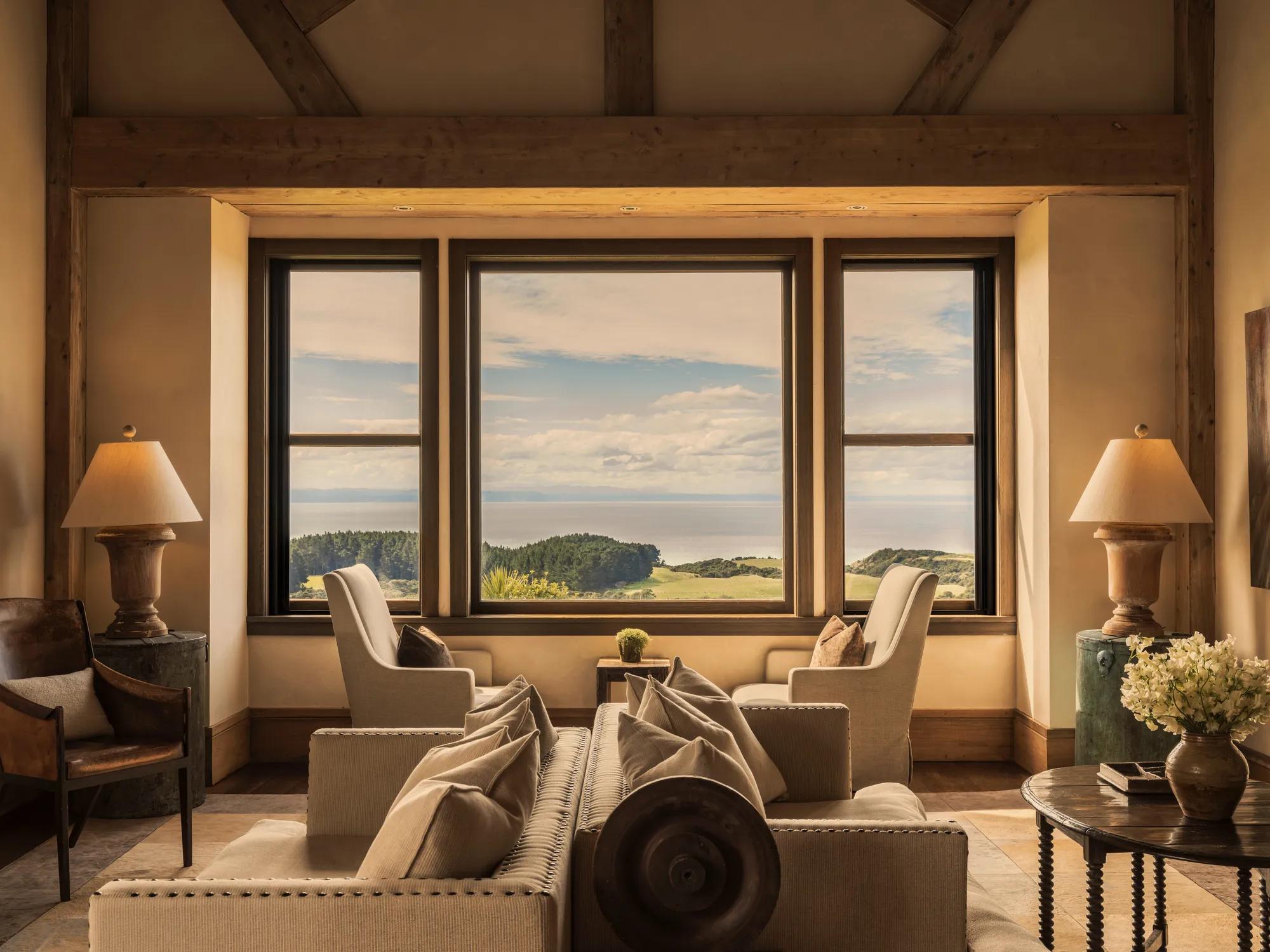 Main lounge at Rosewood Cape Kidnappers with refined countryside interiors and big picture widows with views to the Pacific Ocean.