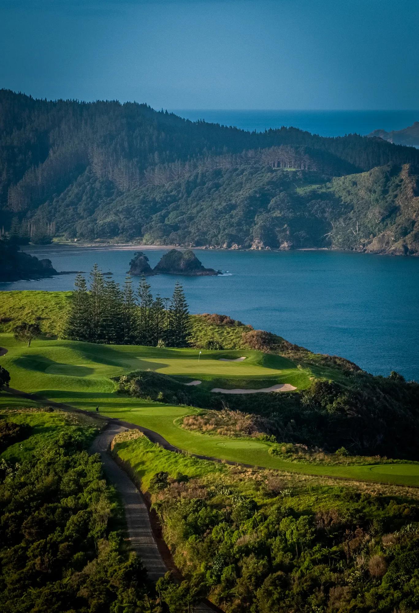 Aerial view over a golf course with scattered islands and the ocean in the background