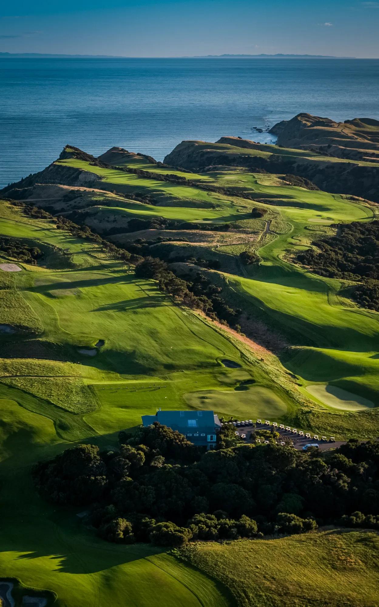 Aerial view over a ridge and valley golf course overlooking the ocean