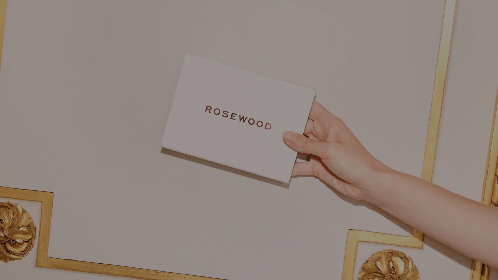 Rosewood-branded gift card partially placed inside an envelope, set on a white marble background