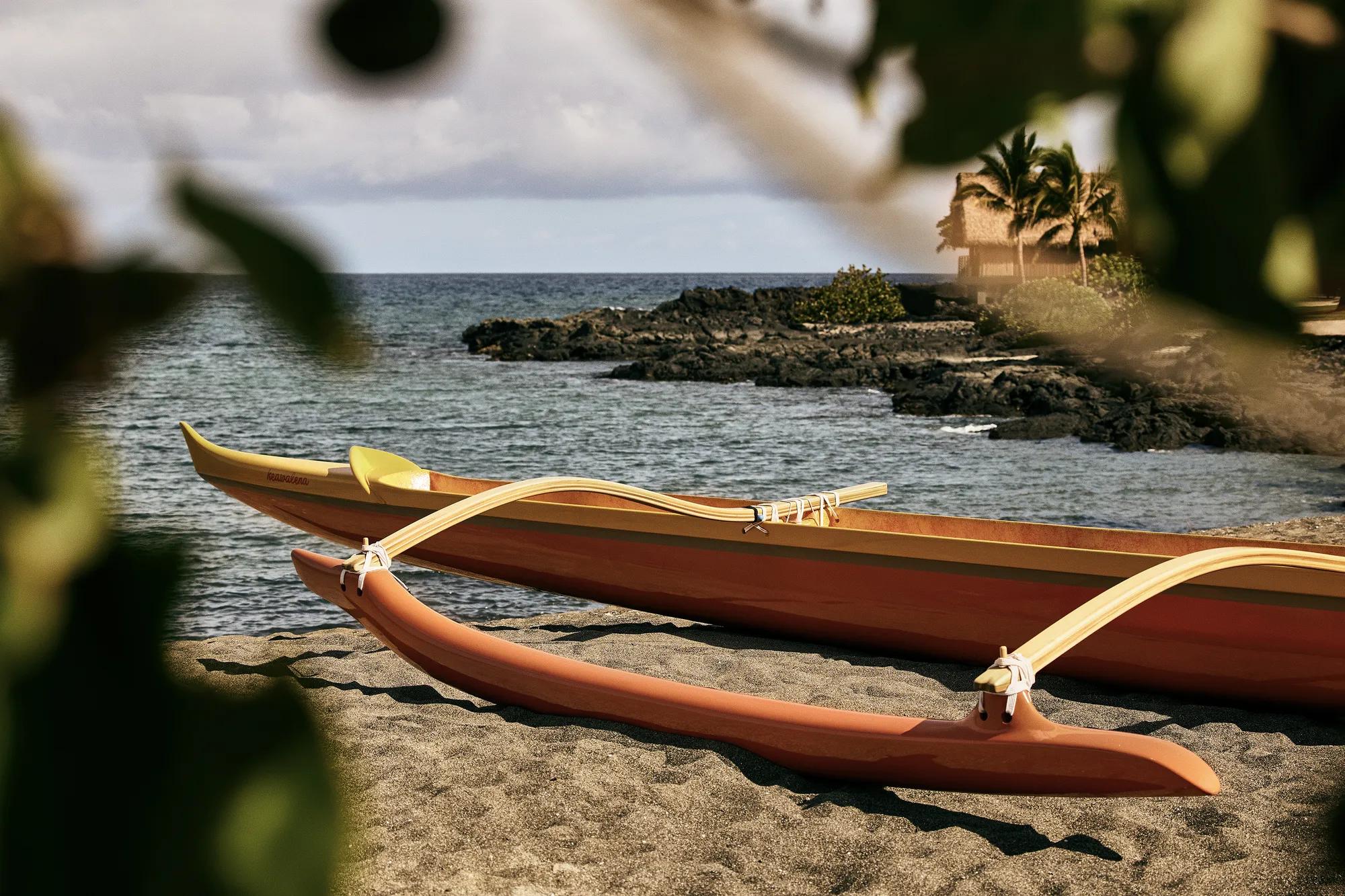 Canoe sitting on shorewith lava rock shoreline in the distance
