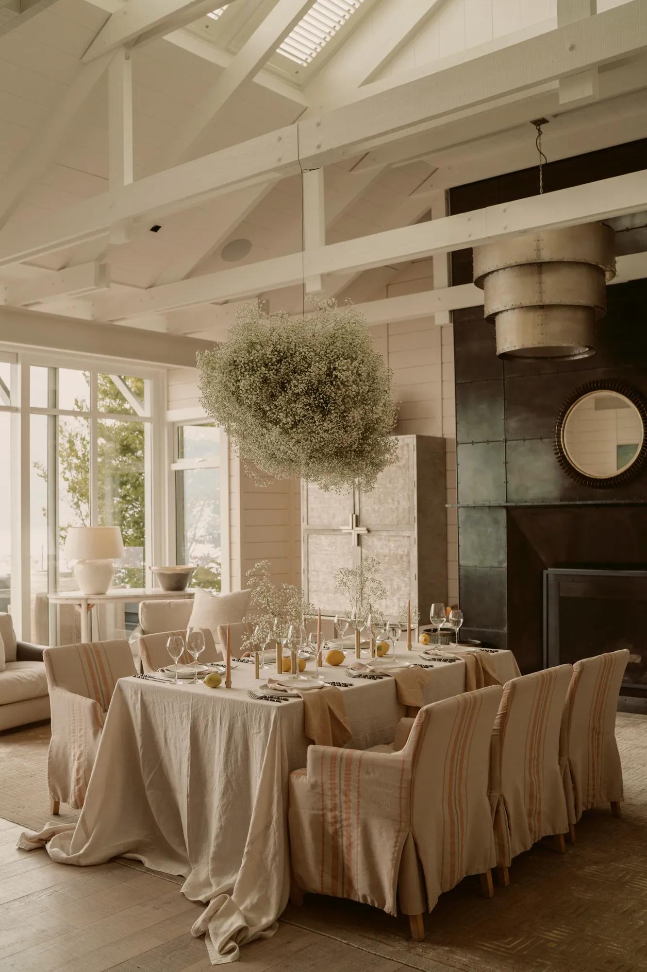 Wedding table set up in a luxury villa at Rosewood Matakauri, with beautifully set table and simple white flower installation above.  