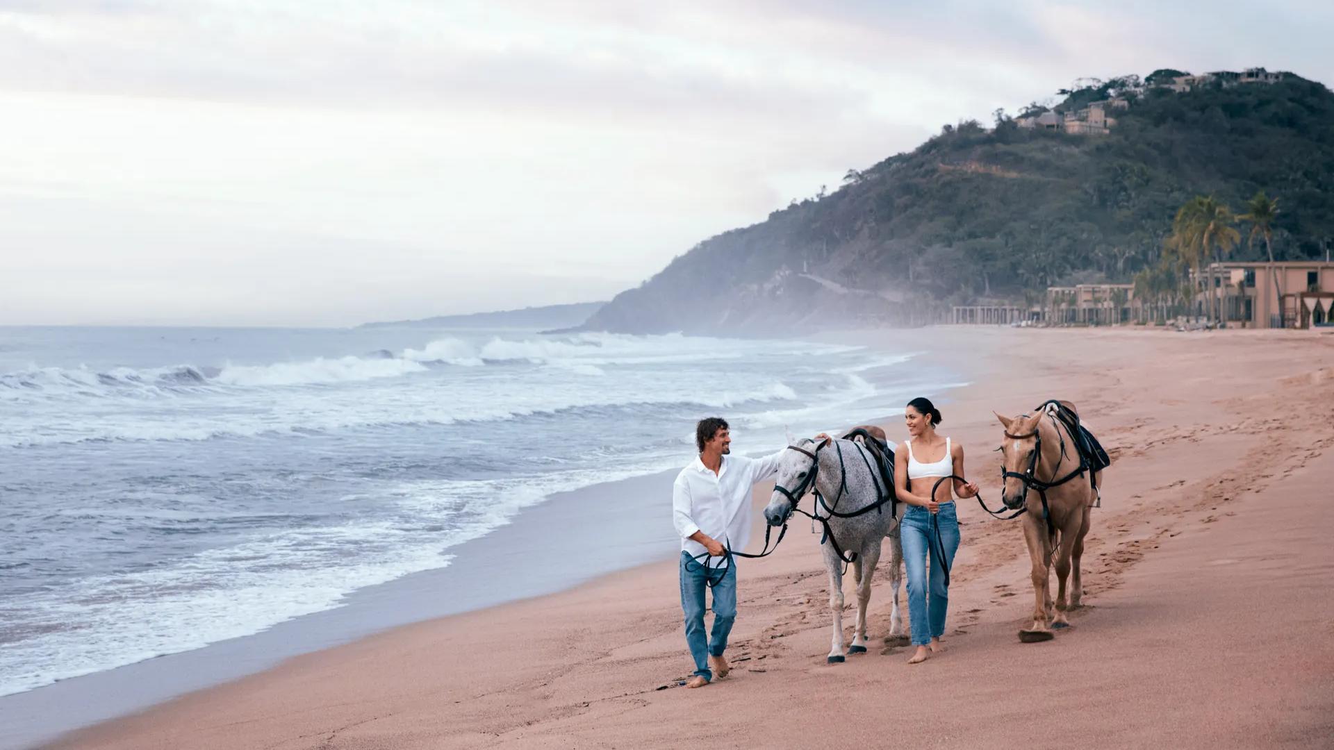 Couple with horses on the beach