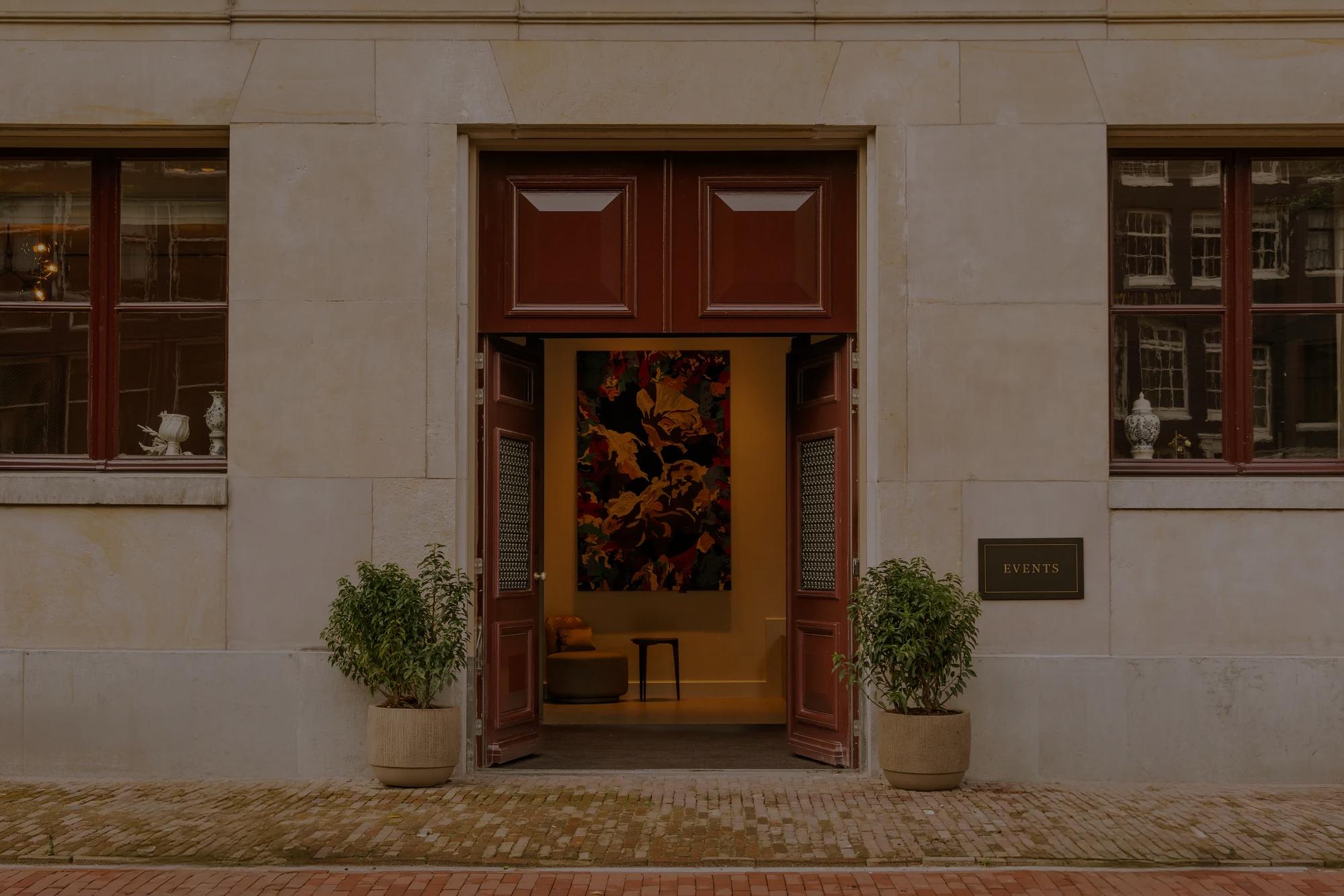 A stone facade with a bronze plaque named Events with large open wooden and iron doors,  
