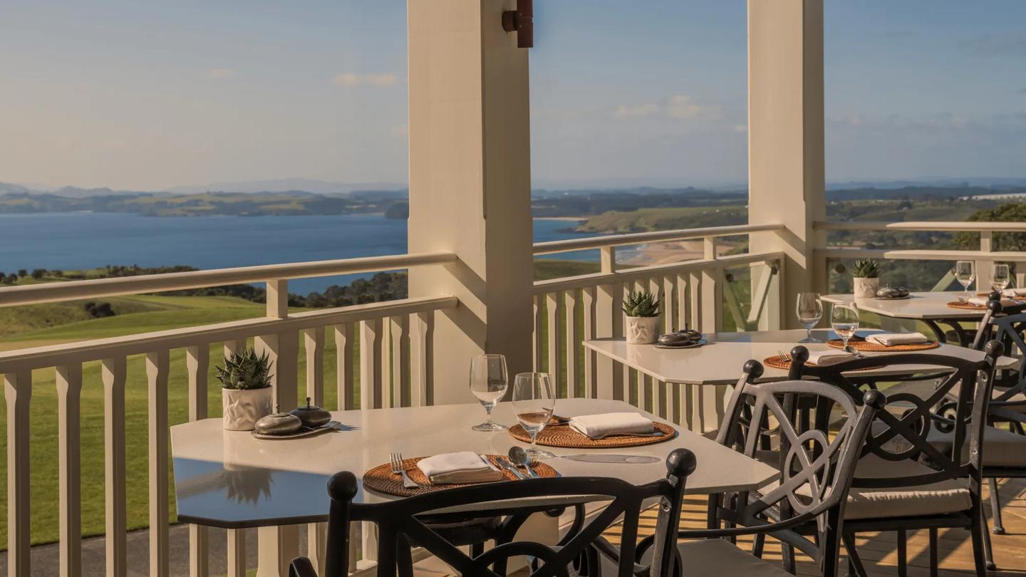 Outdoor dining on the balcony at Rosewood Kauri Cliffs overlooking the golf course and Bay of Islands.