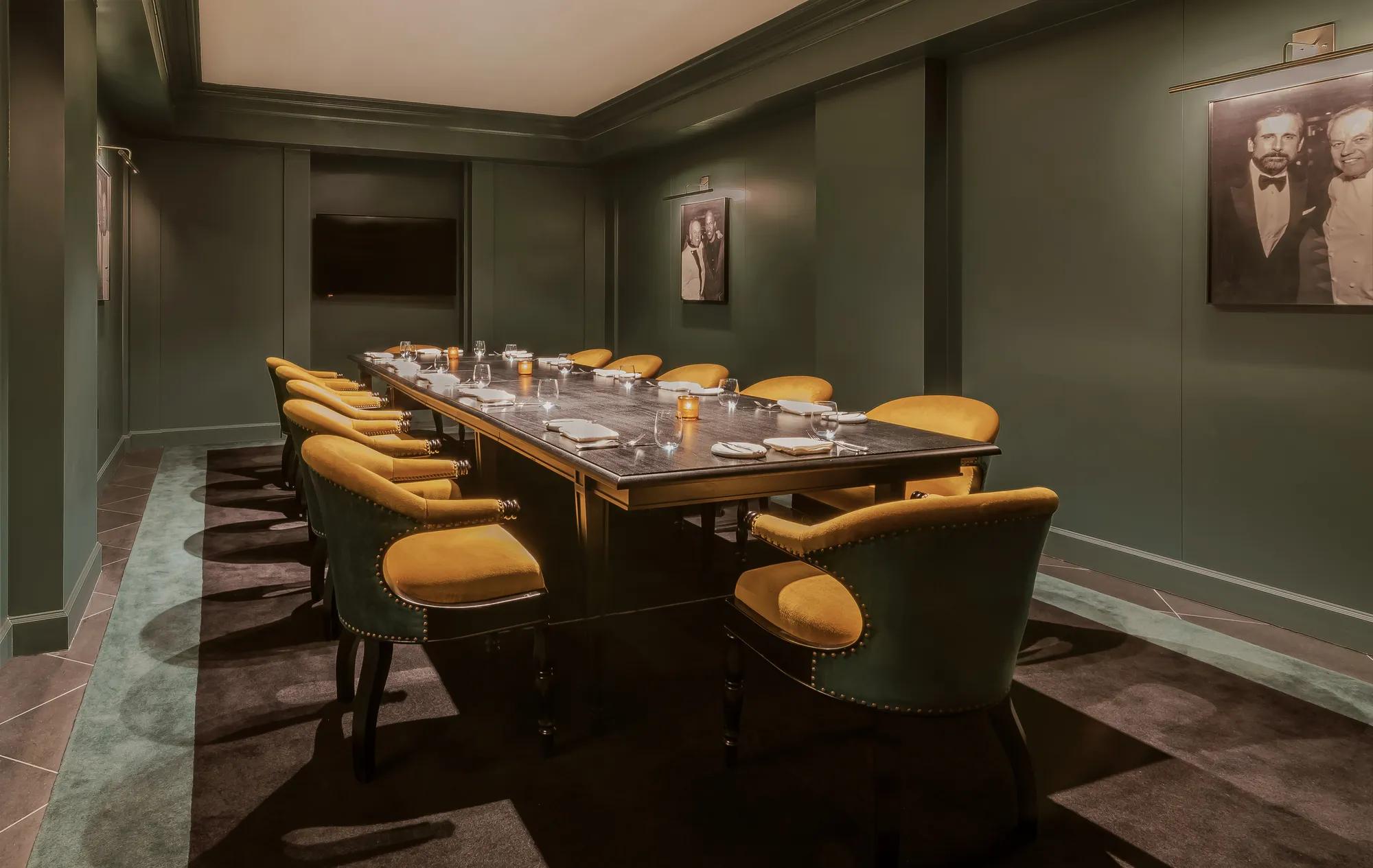 Private dining room with green walls, yellow chairs and a black table 