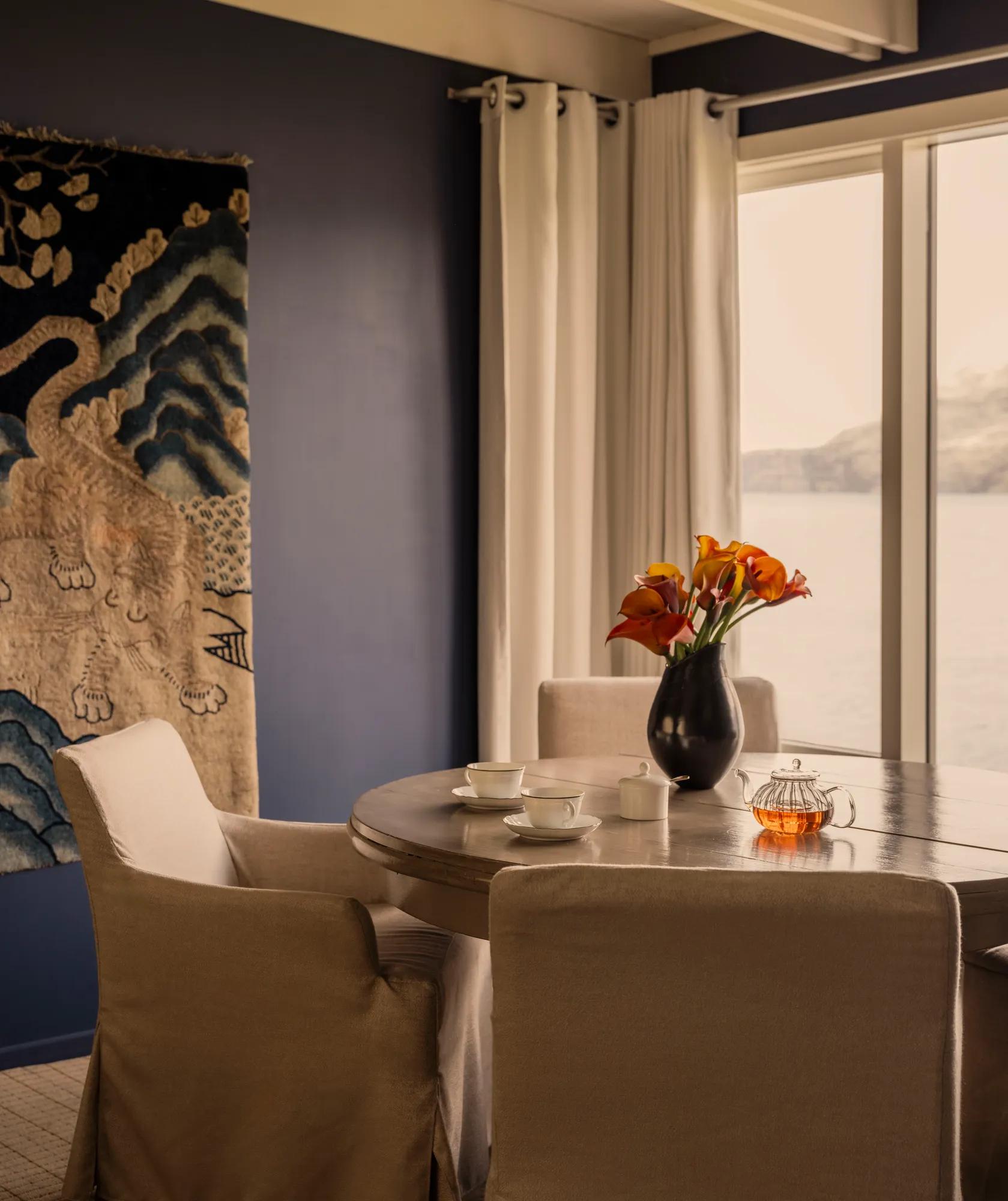 Dining table in the library at Rosewood Matakauri with a ancient tiger tapestry on the wall and lake and mountain views.