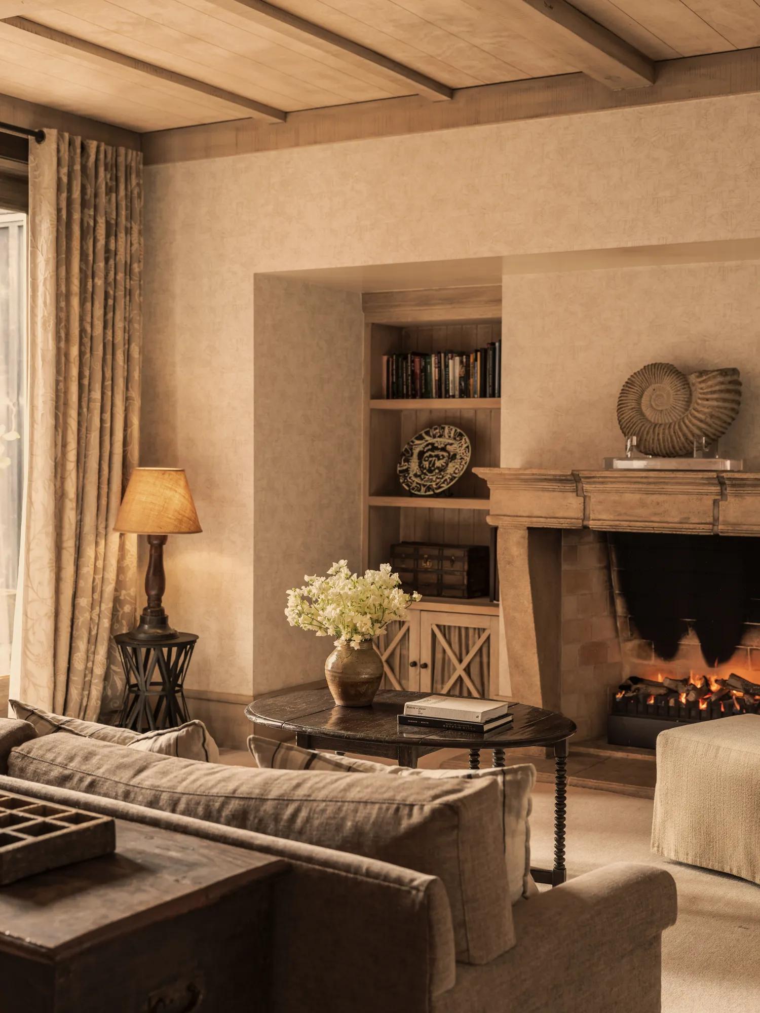 Cosy library at Rosewood Cape Kidnappers with comfortable seating, open fire and shelves lined with books, art and artifacts.