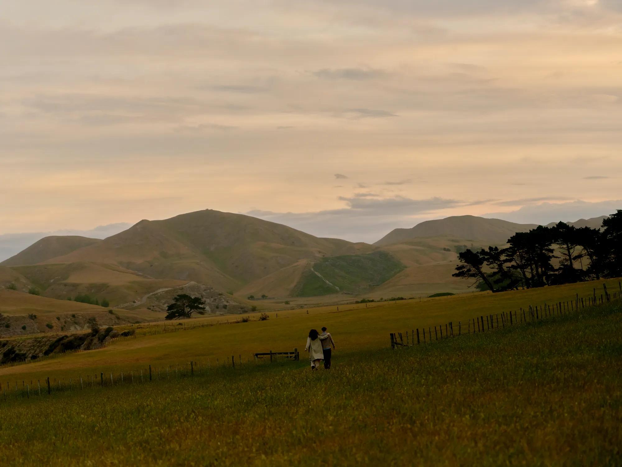 Couple walking in countryside setting with rolling hills in the distance
