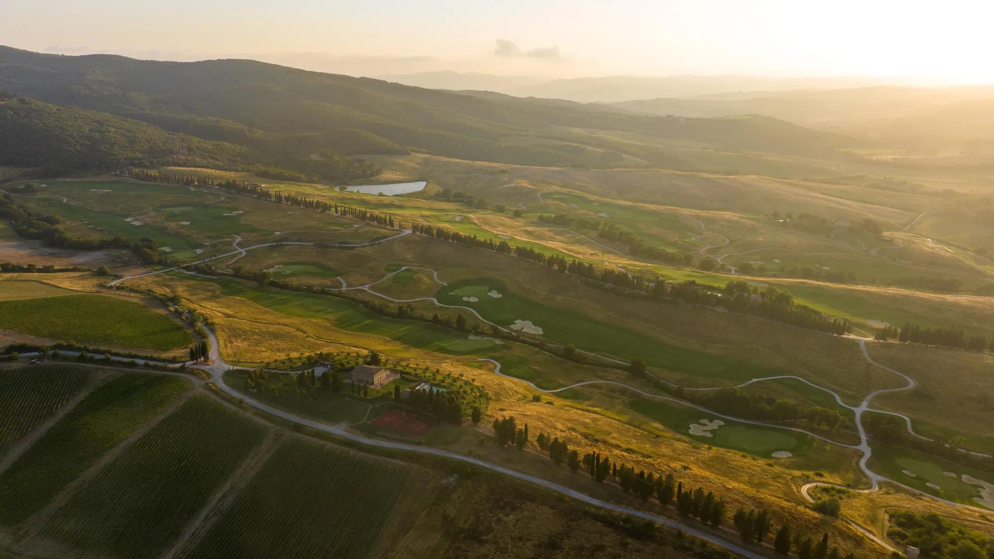 Tuscan countryside retreat with rolling hills,  trees, and a tranquil lake.