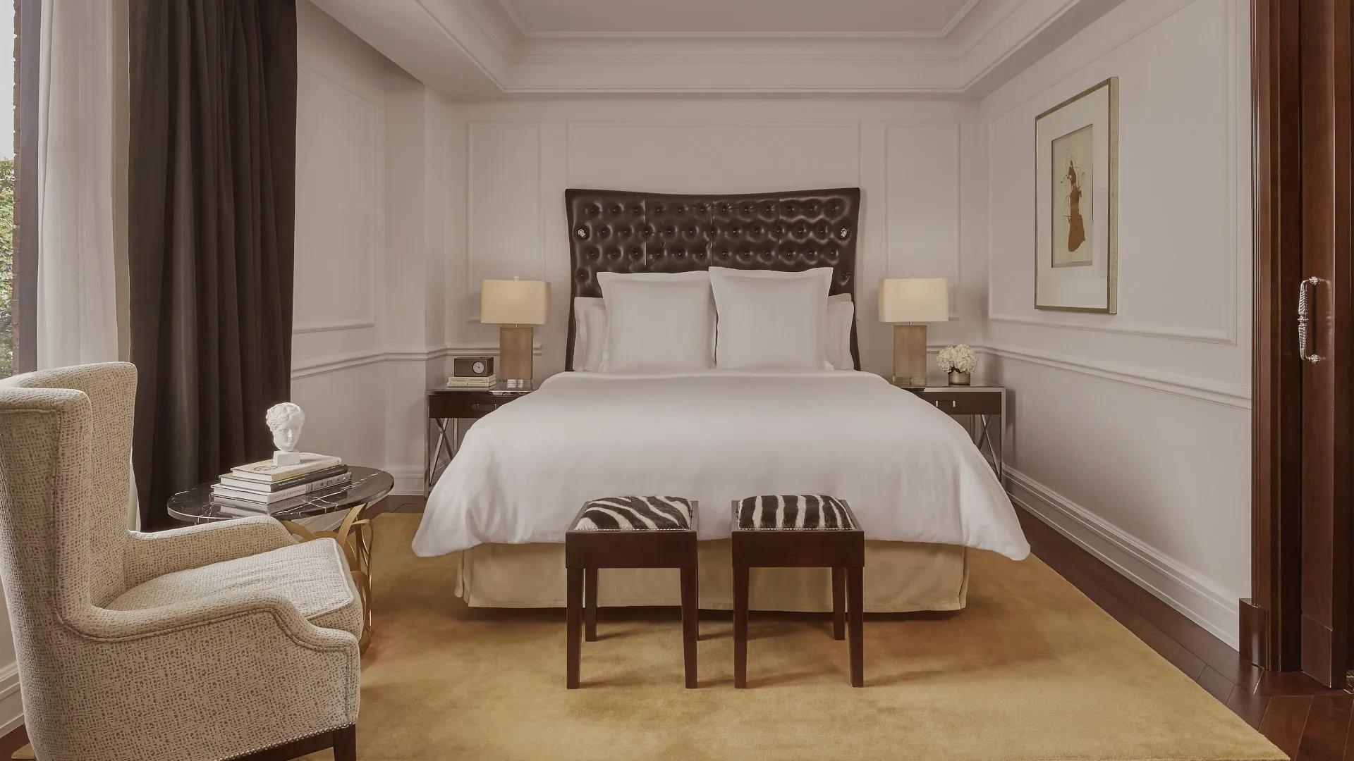 King bed in a spacious room with two nightstands, lamps, and two zebra patterned stools.  