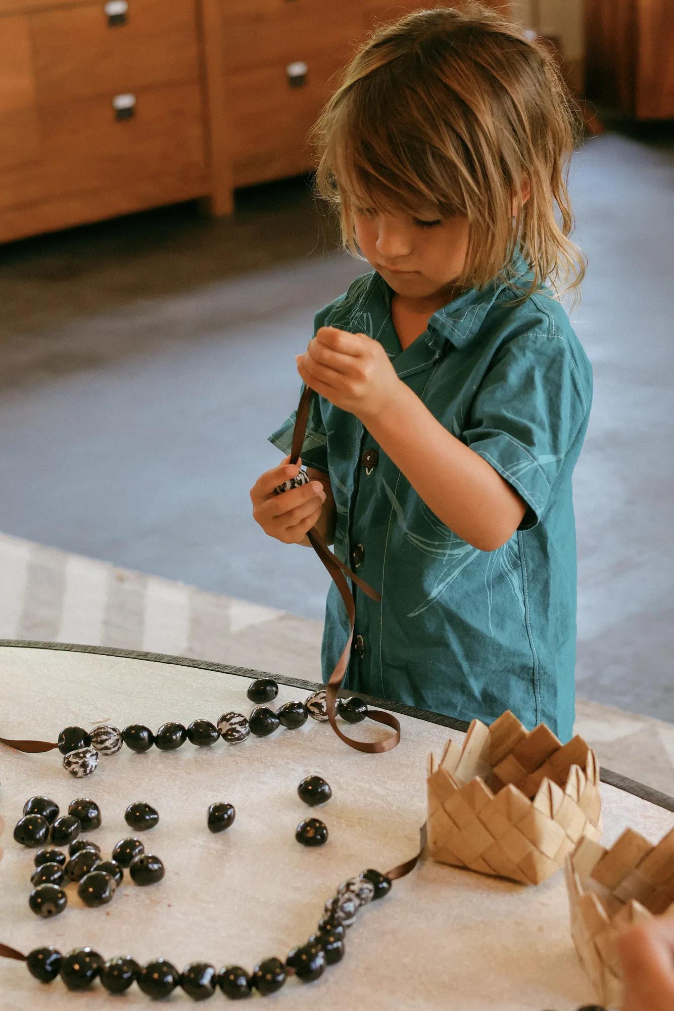 Small keiki making kukui nut lei