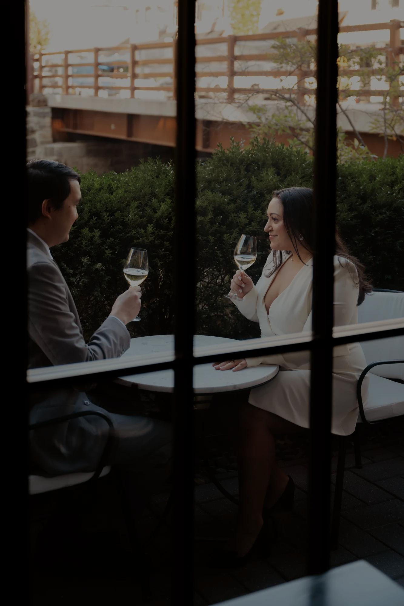 Looking through patio doors at a couple who just got engaged, toasting to the occasion