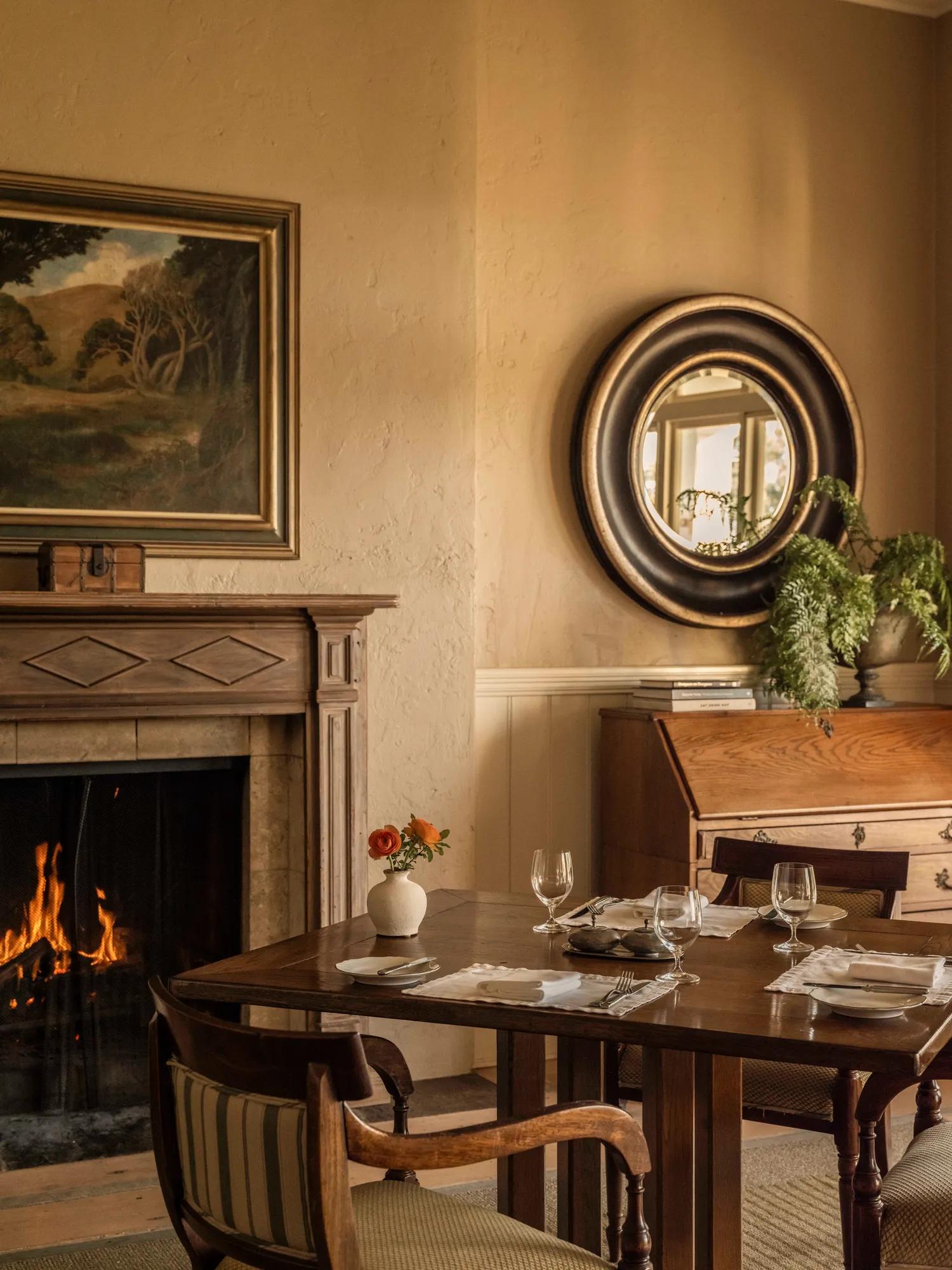 Classically styled dining room, with timber dining table and an ornate open fireplace.