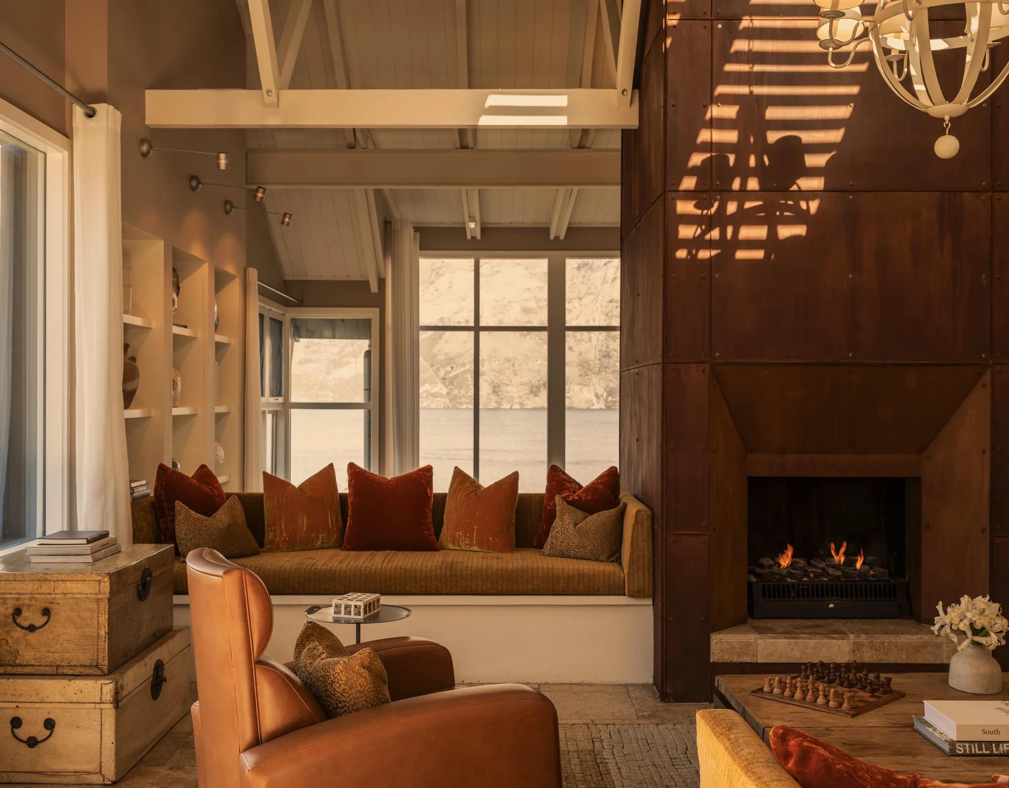 Inviting sitting area at Rosewood Matakauri with open fire with Corten steel surrounds and distant views of Lake Wakatipu.