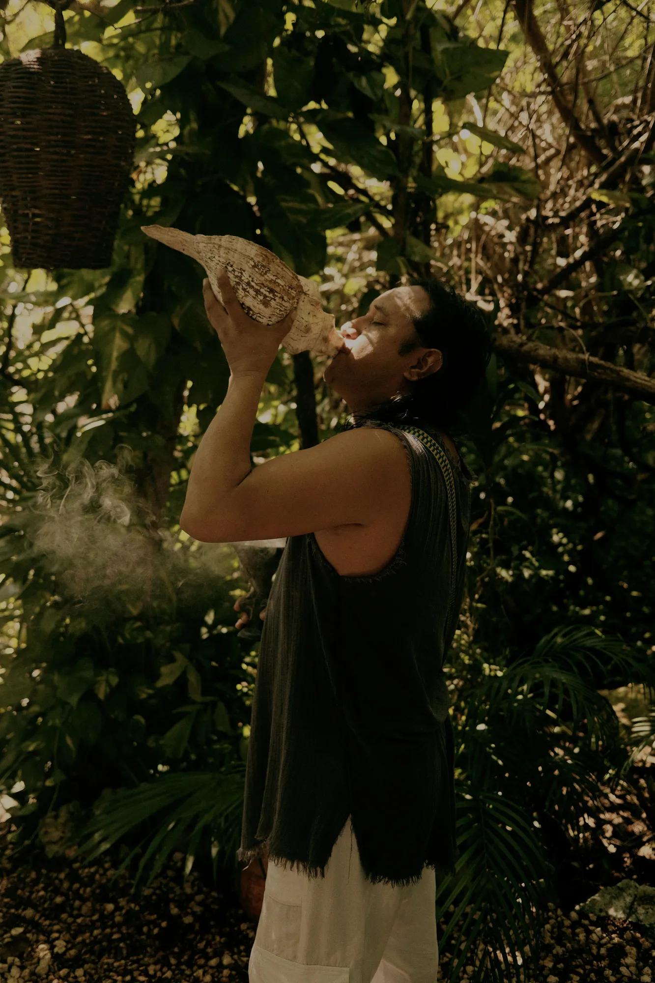 Mexican shaman performing a copal ceremony under a cloudy sky, in a spiritual outdoor setting with traditional elements.