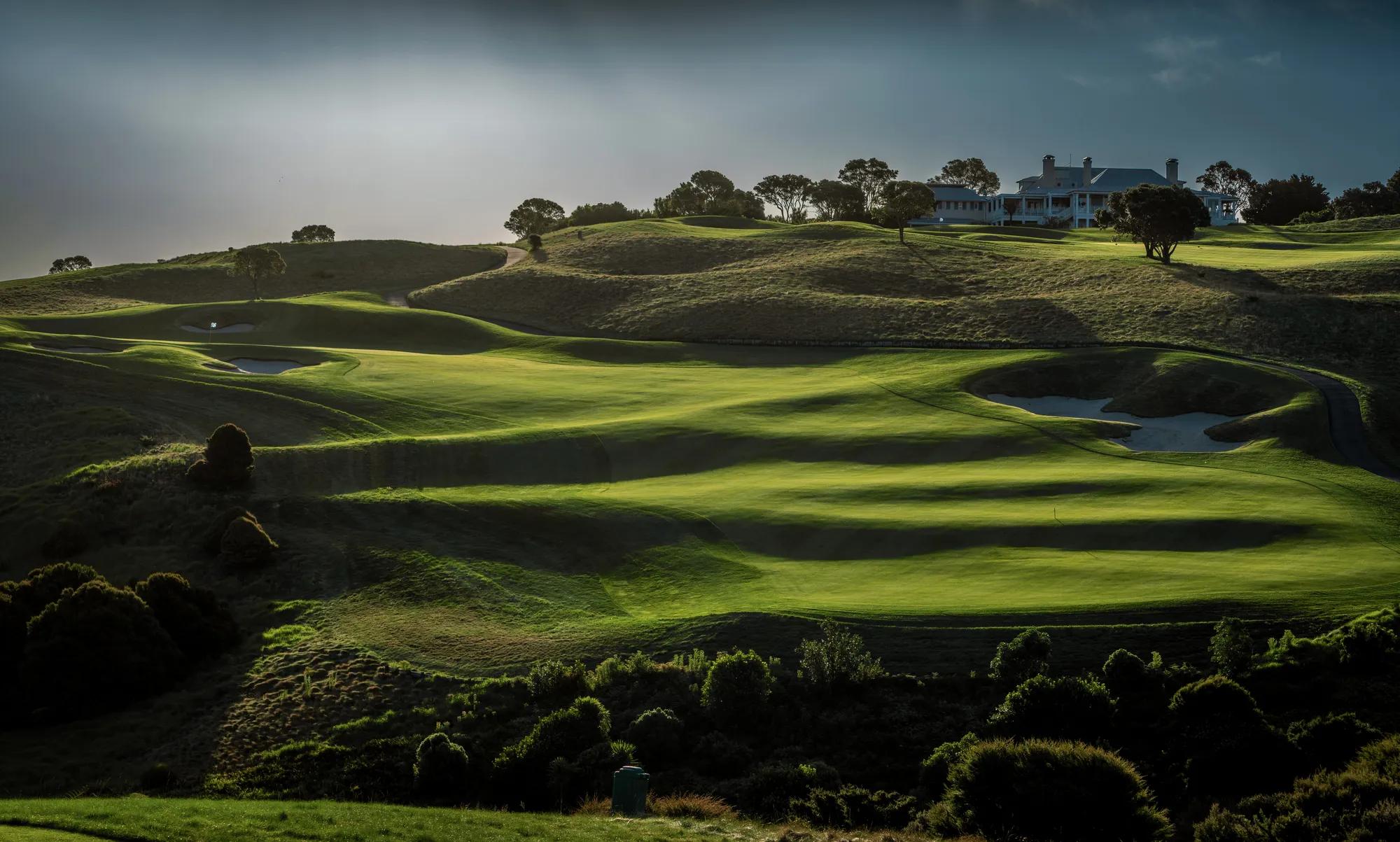 Striking scene of the undulating landscape of the in;and golf holes, with a moody sky and dramatic shadows. 
