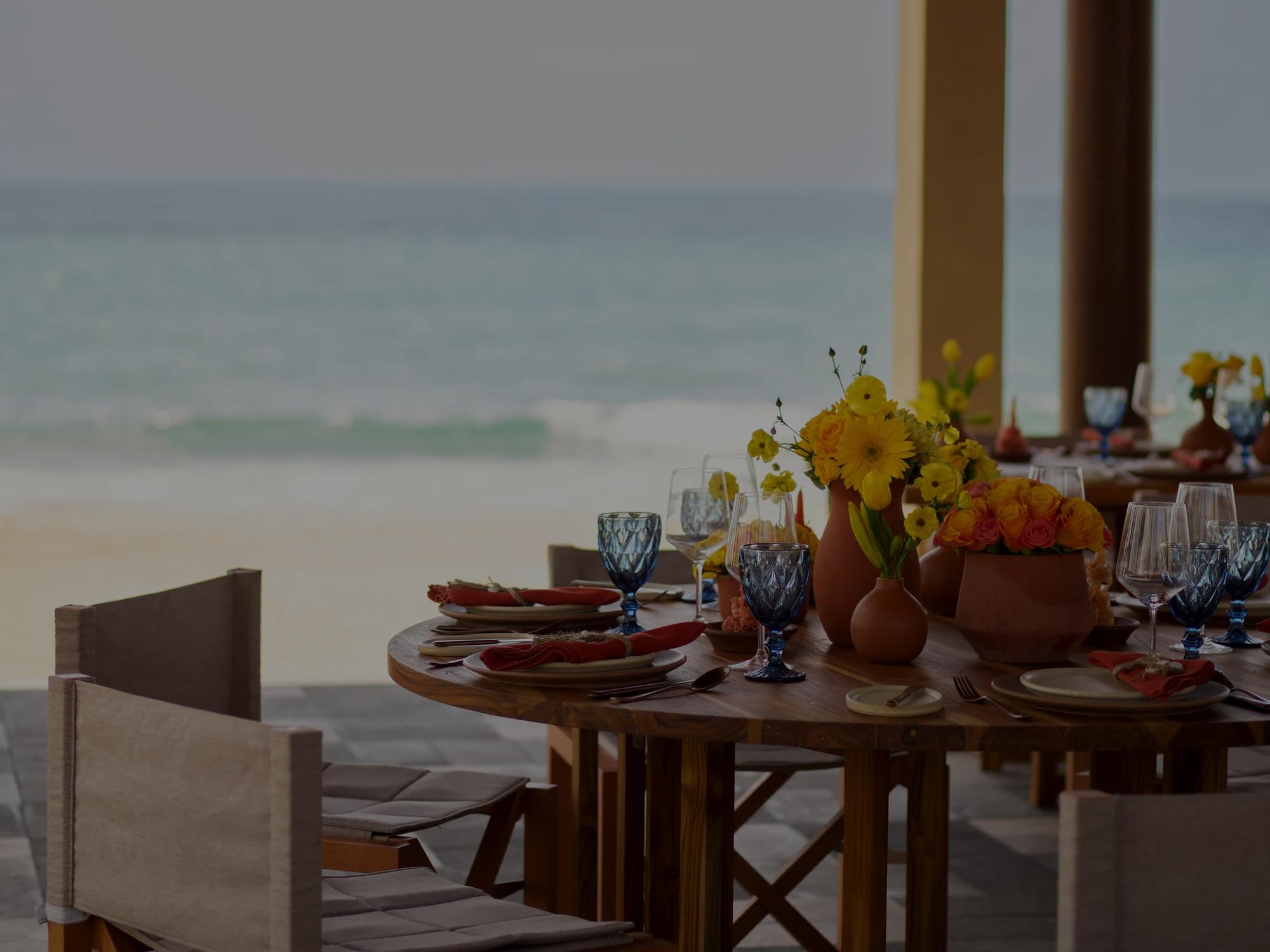 Table decorated with flowers, plates and wine glasses with the ocean as background
