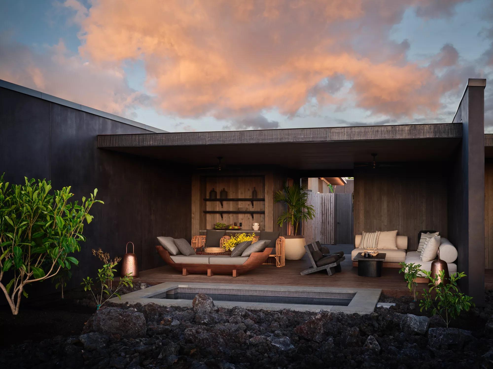A spa lounge at sunset with seating and a plunge pool among lava rock