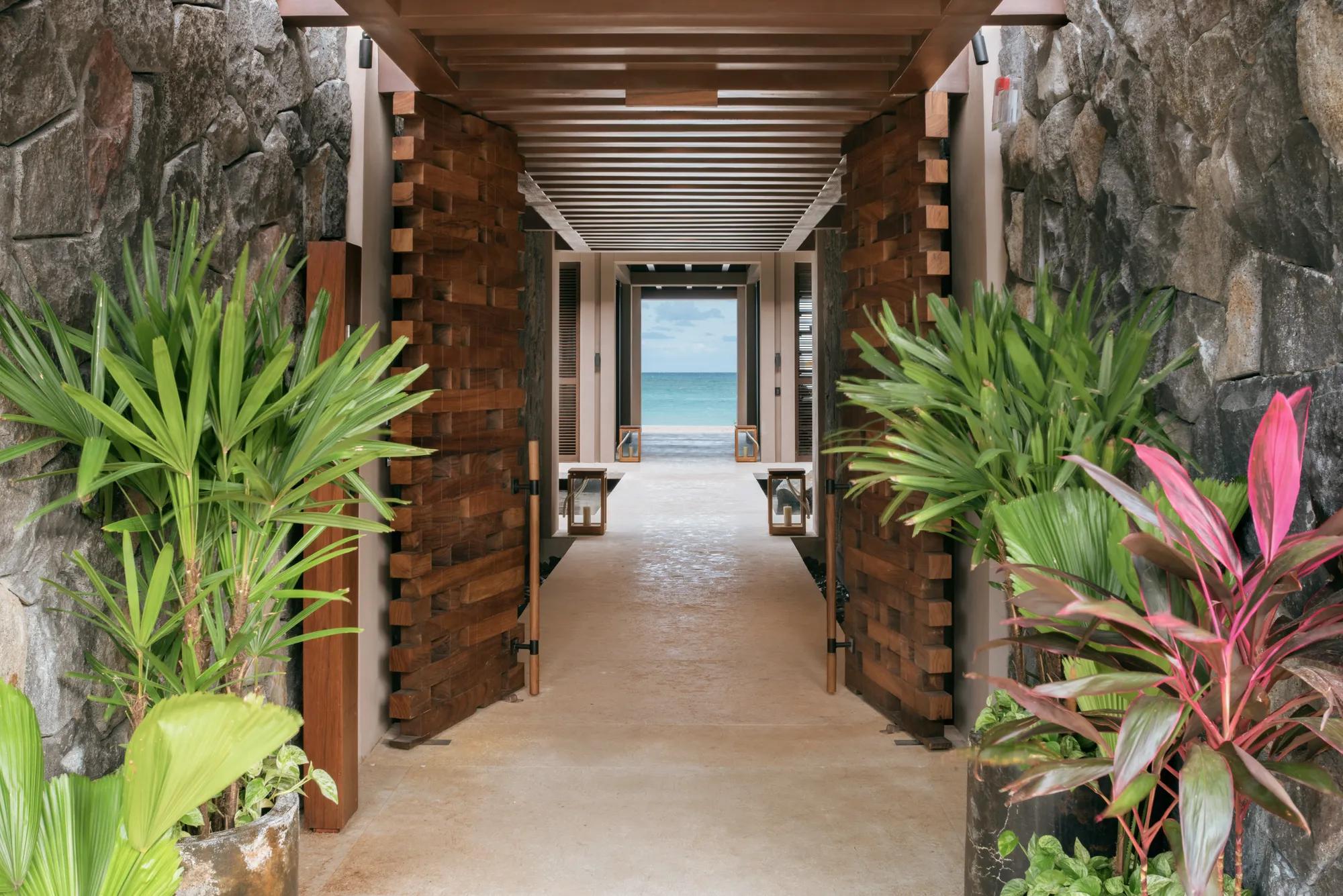 Front driveway to Rosewood Mayakoba, lined with lush tropical greenery and leading to the elegant motor lobby