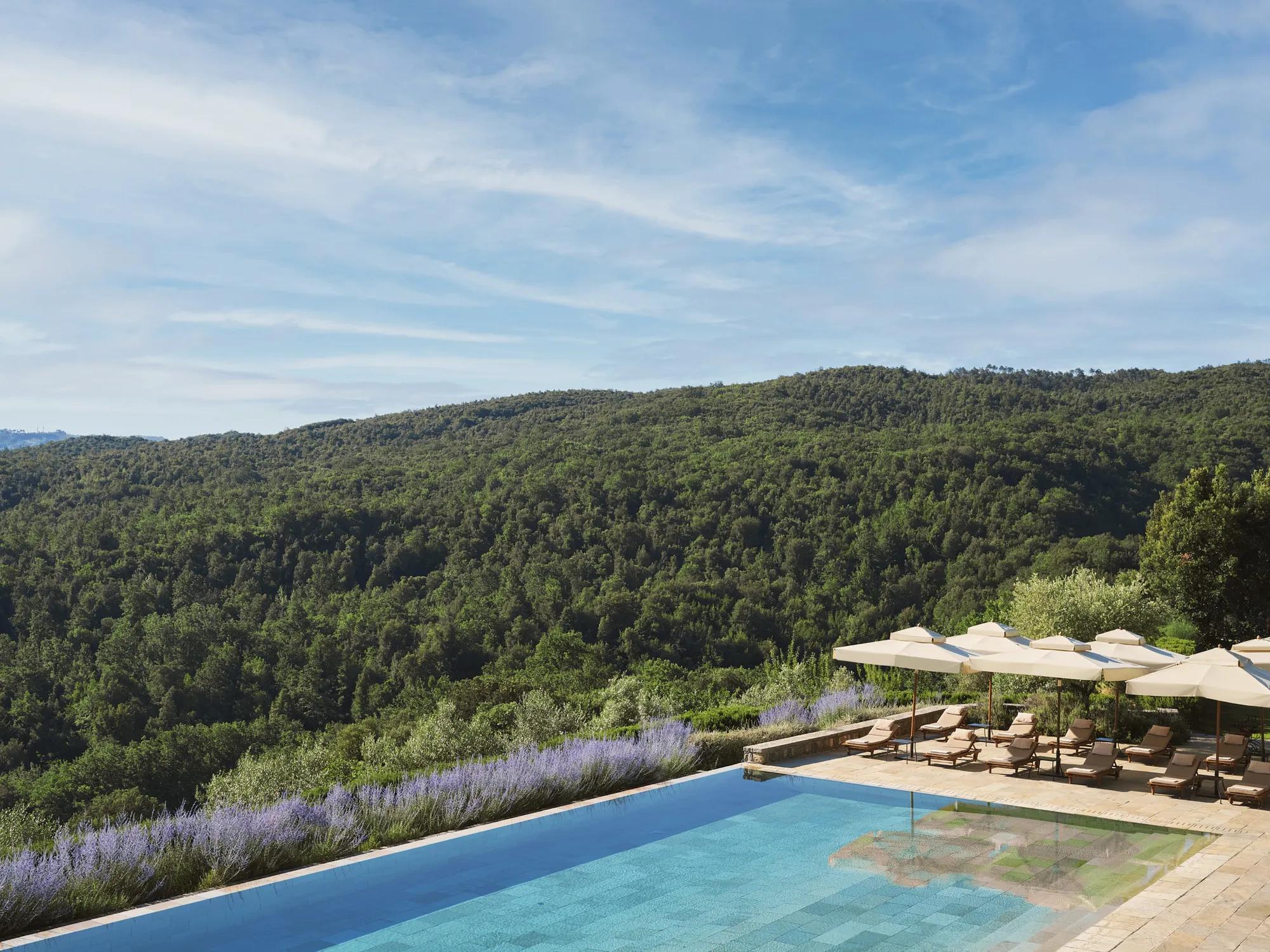 Infinity pool with Val d’Orcia views and surrounding woods.
