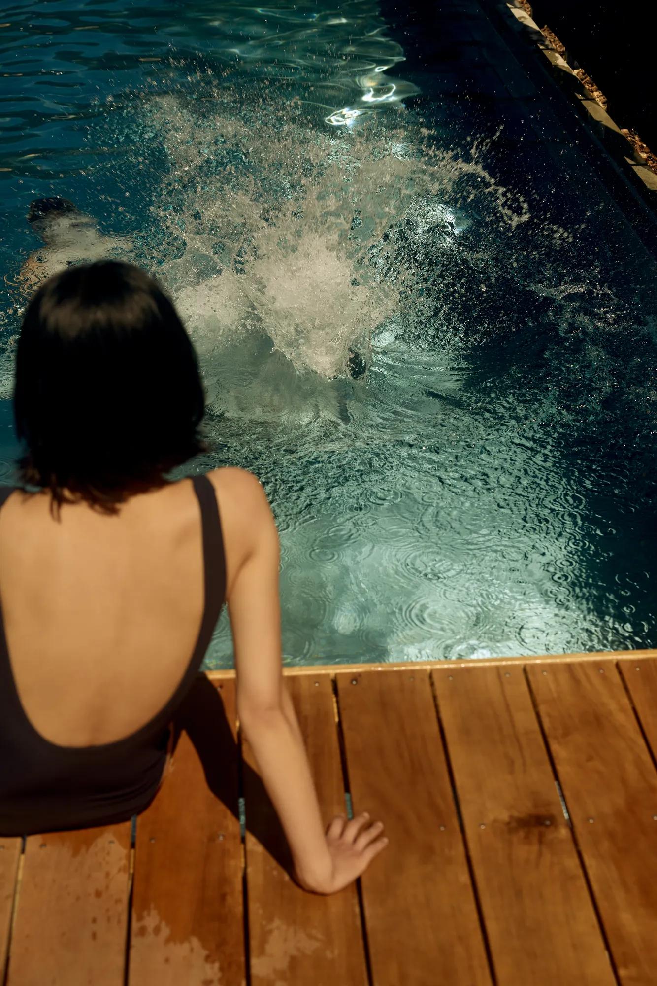 View looking out from the outdoor cedar sauna towards the outdoor pool at Rosewood Matakauri with lake and mountain view.