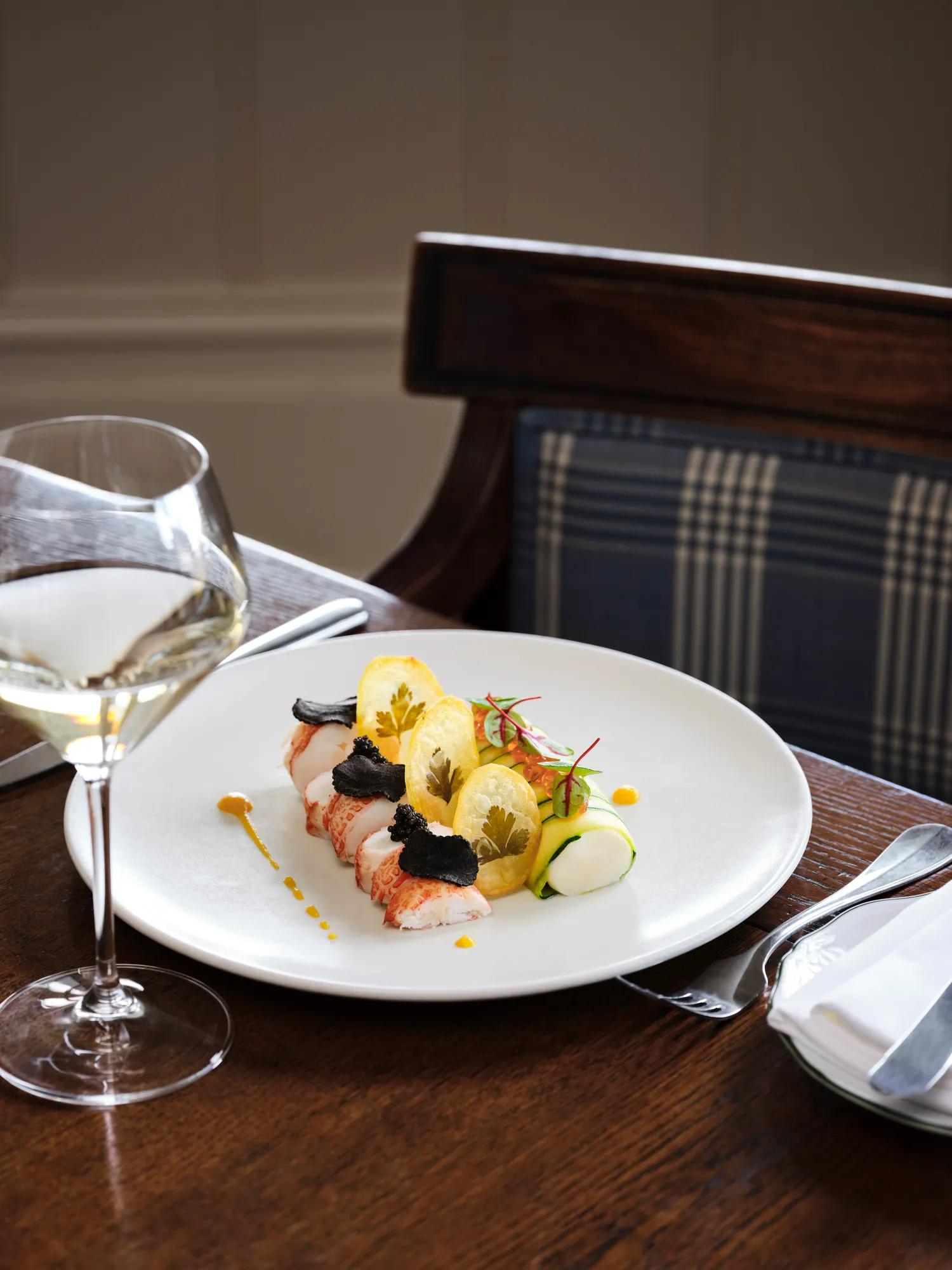 Plated crayfish dish in a fine dining restaurant, served on white china with a glass of chilled white wine.