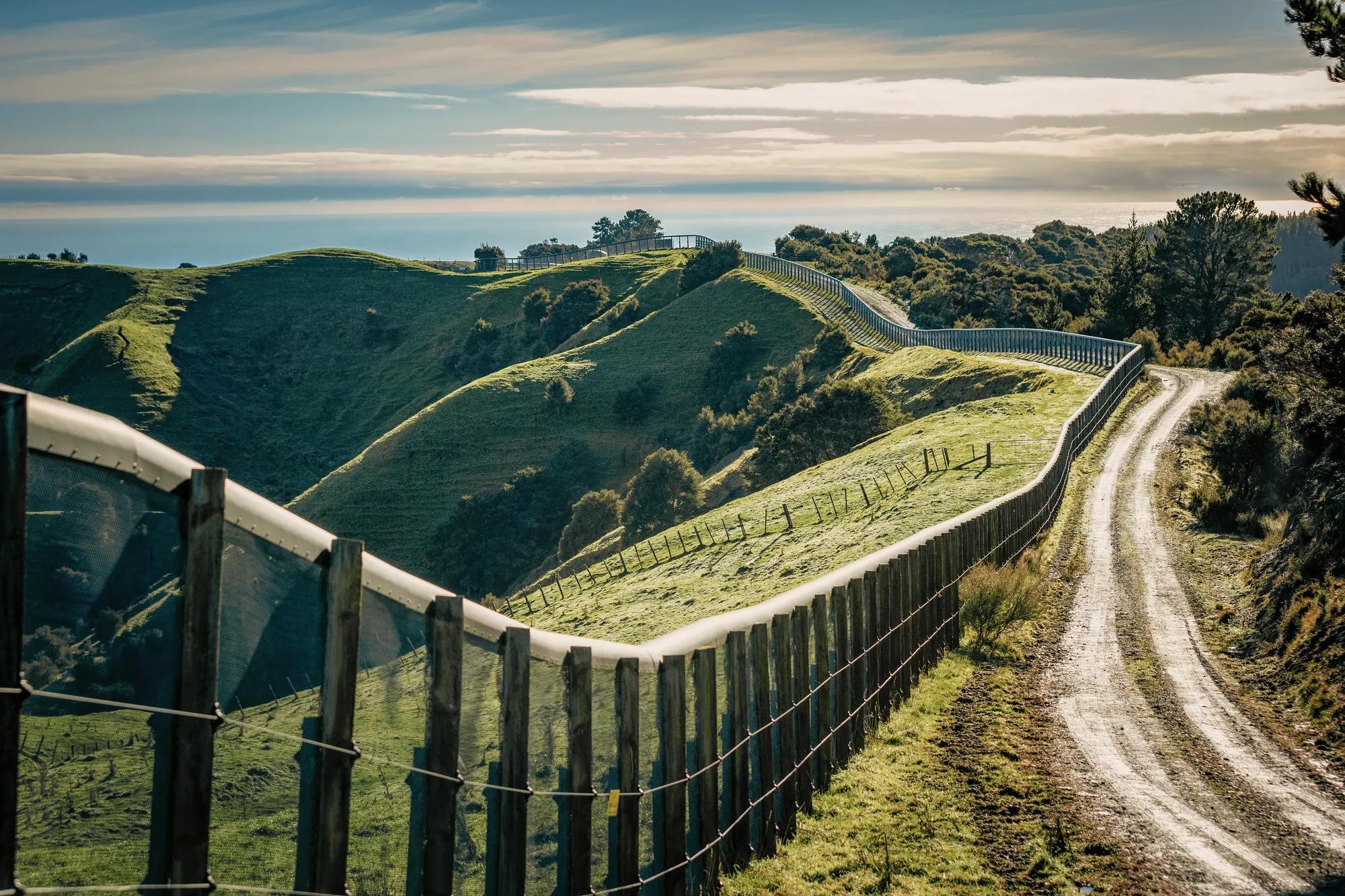 Predator proof fence with a wildlife sanctuary on one side and rolling farmland on the other.