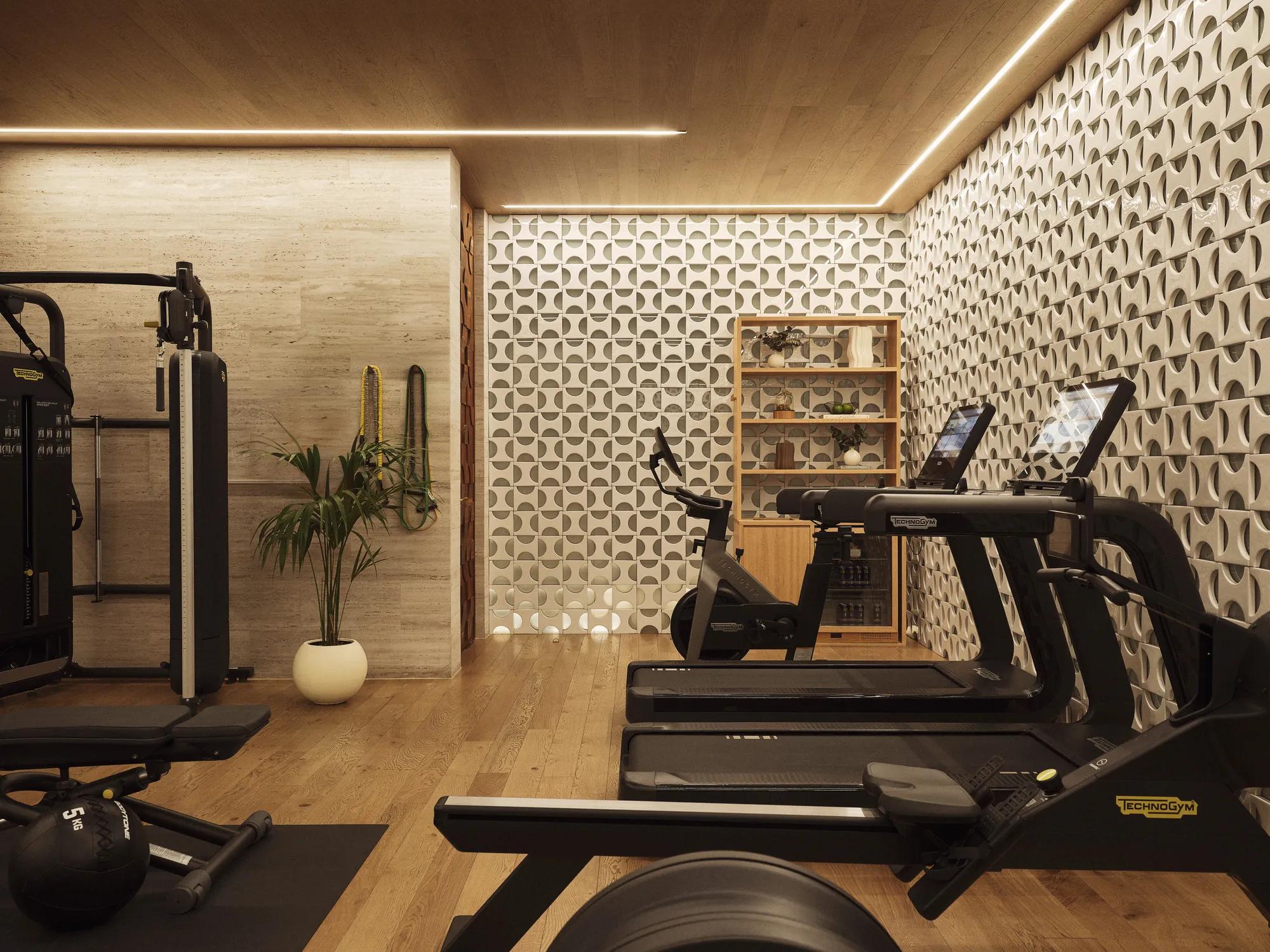 Fitness room equipped with a running machine, free weights, and an exercise ball, arranged in a clean and well-lit space