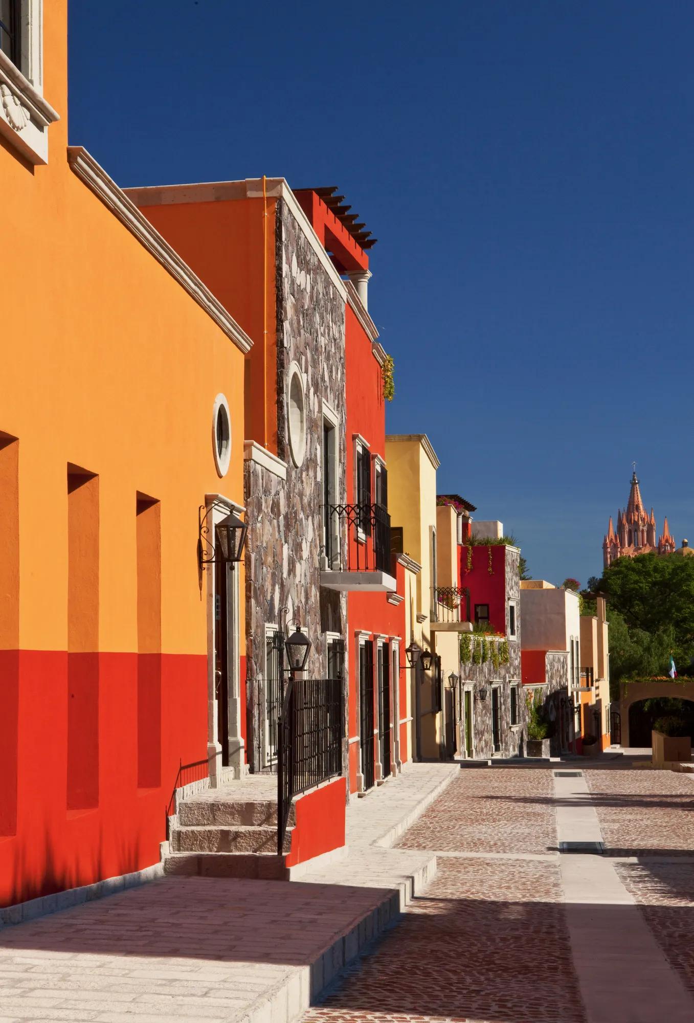 Rosewood Residences in San Miguel de Allende showcasing vibrant colonial architecture and views of the iconic parish in the distance. 