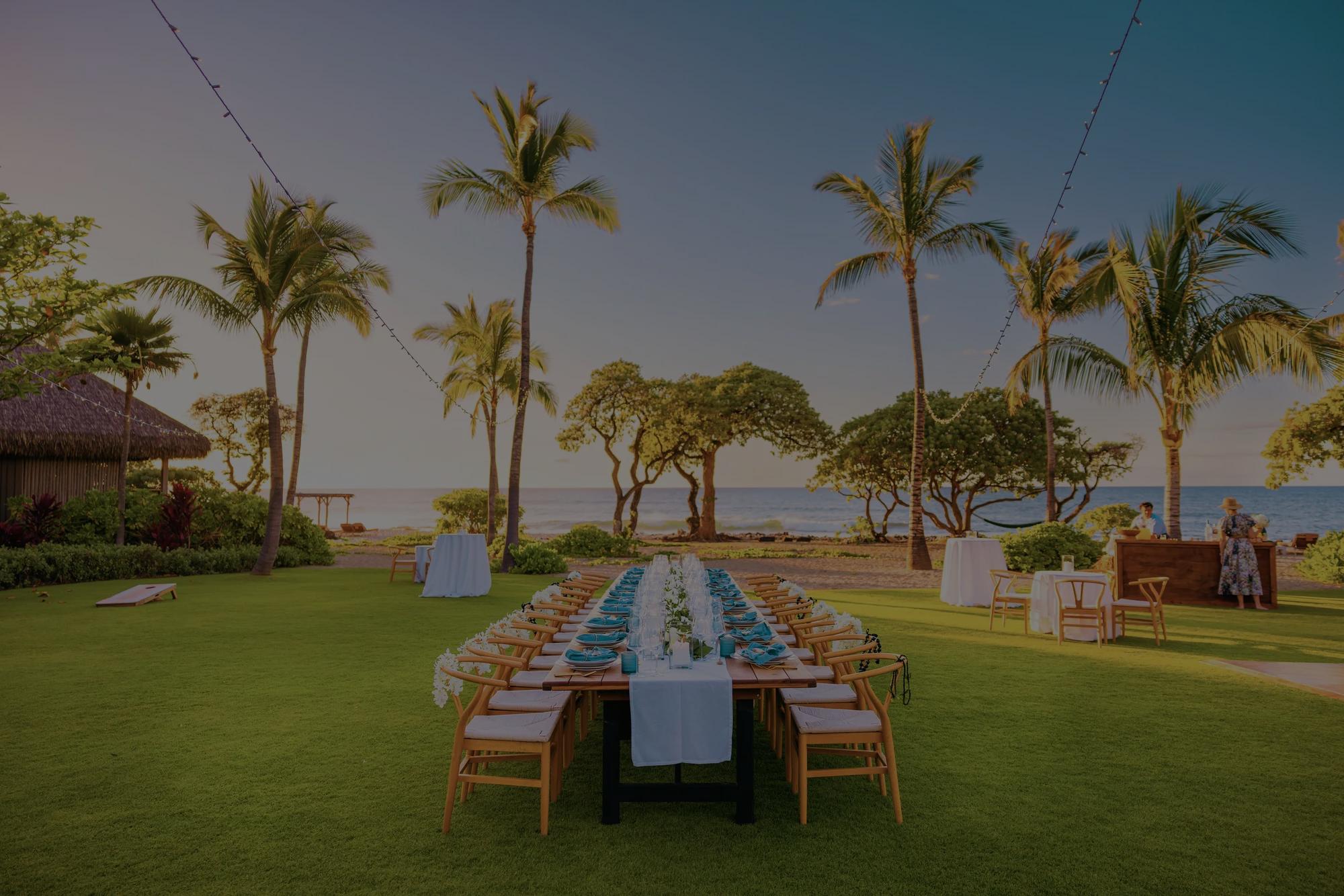 A long table set for an event on a lawn next to the beach