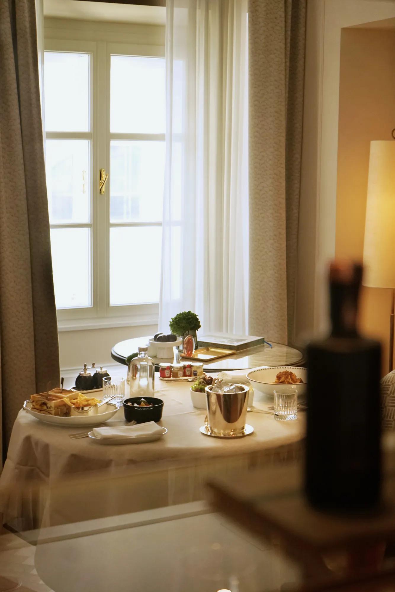 A man in a suit is pouring red wine from a  bottle into a glass.