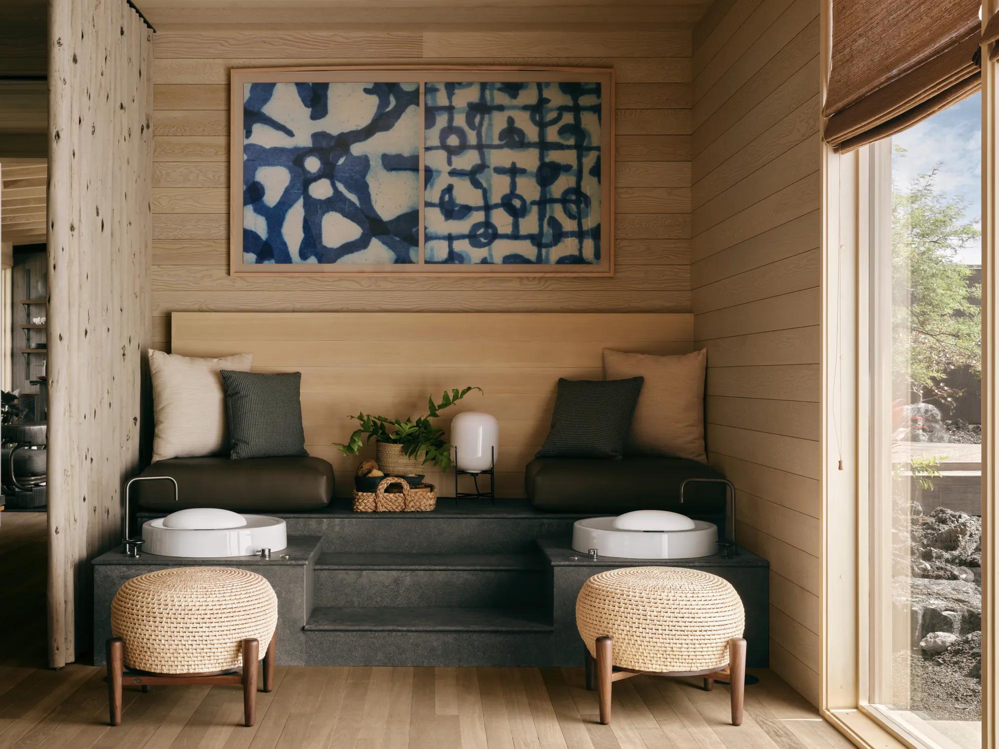 A bench with two pedicure stations in a modern looking salon with a floor to ceiling window.