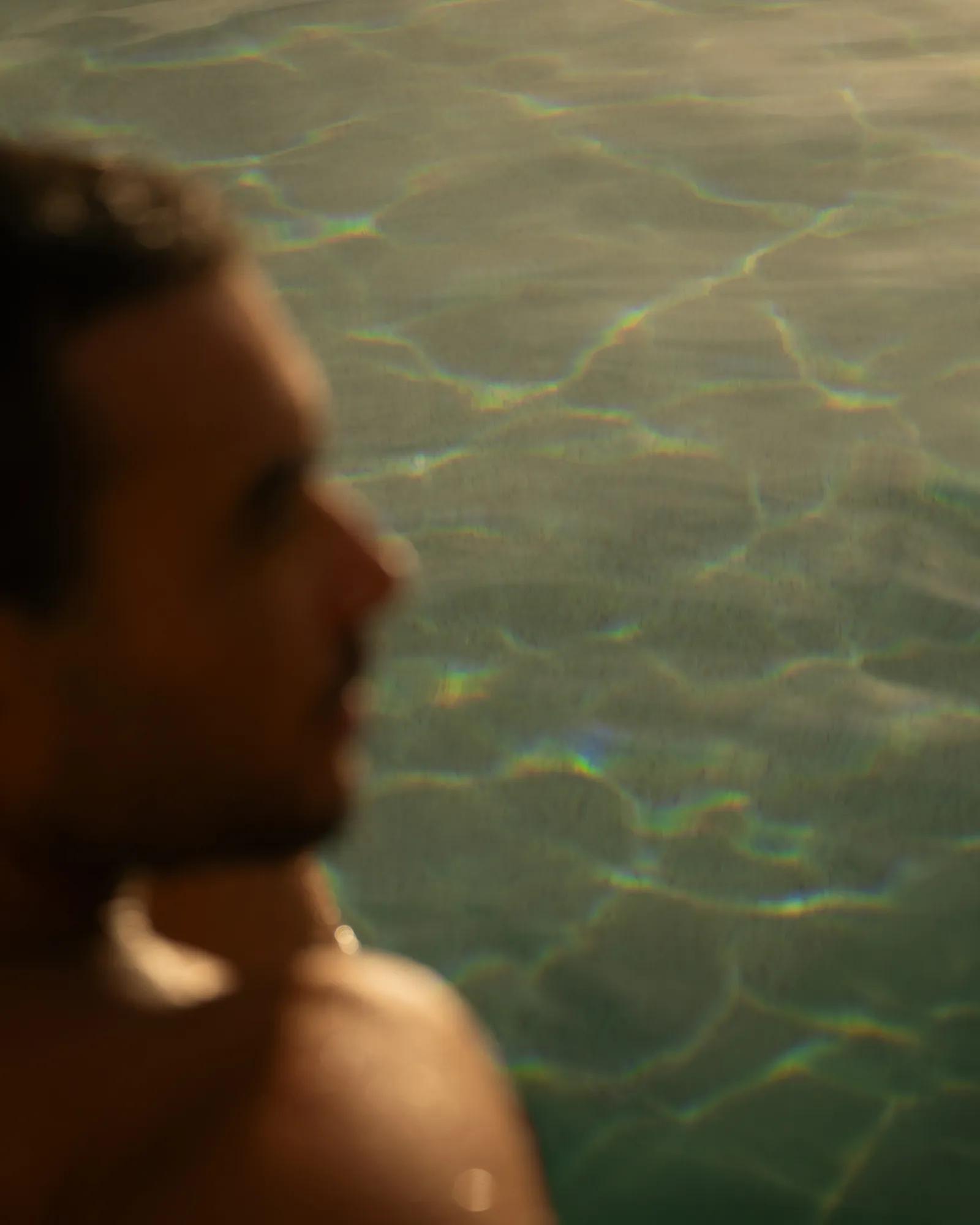 Outdoor spa area with a massage table, cushioned seating, tropical plants, and palm trees creating a serene and private atmosphere.