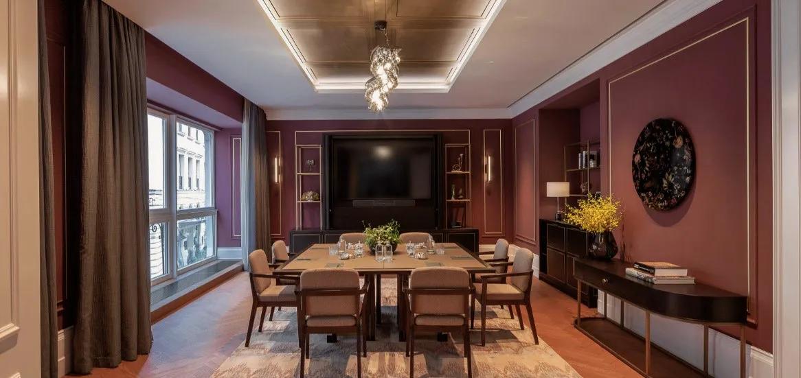 Elegant event space at Rosewood Vienna with blue paneled walls, large windows, round dining tables set for a formal gathering, and contemporary lighting accents.