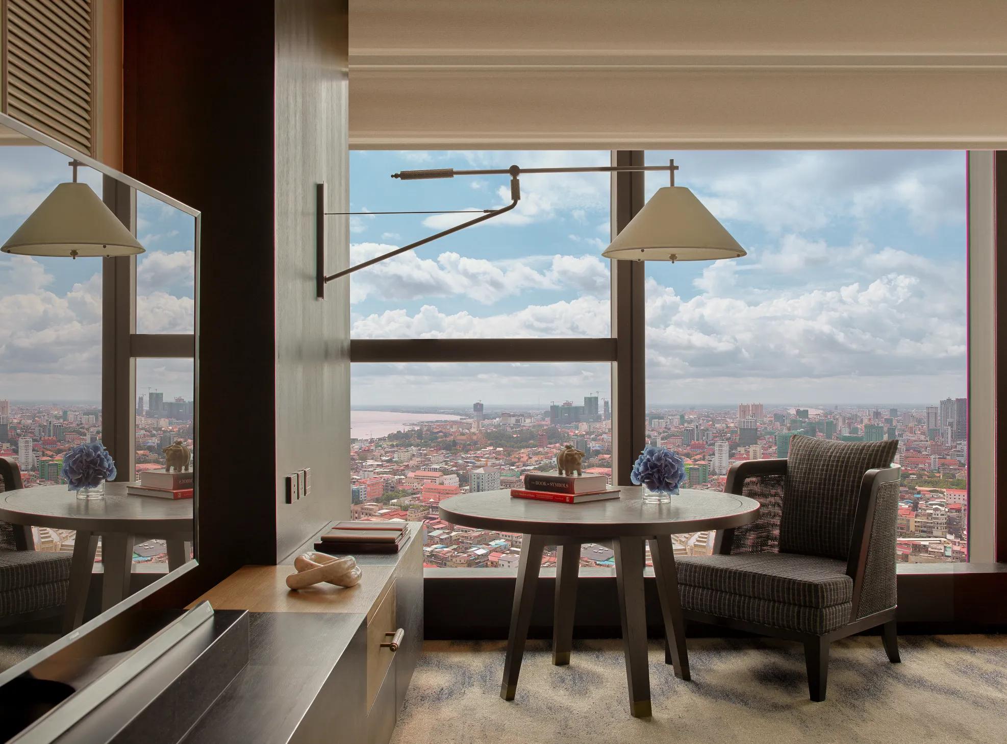 Hotel room with  floor-to-ceiling windows  overlooking the city skyline. 