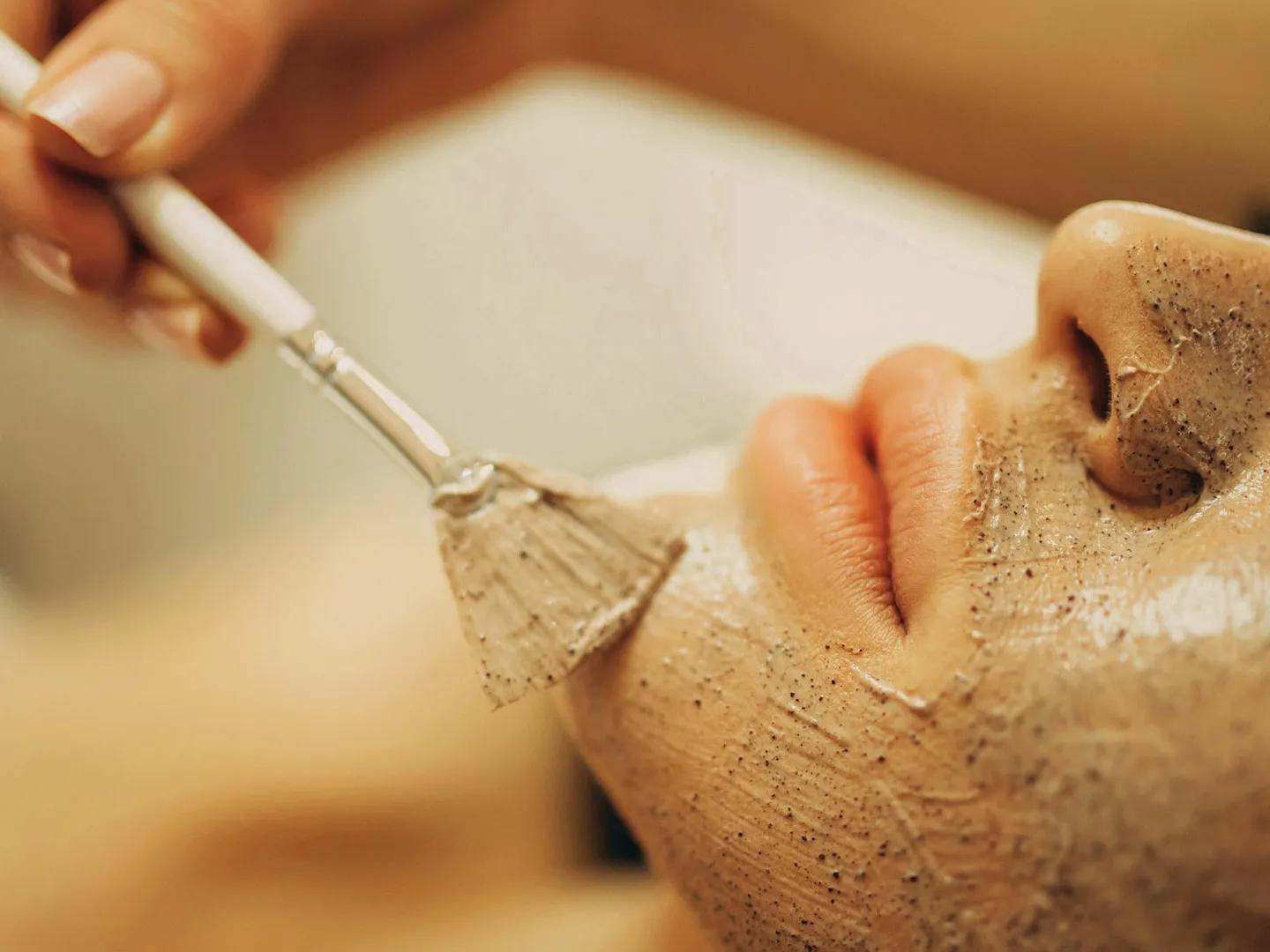 Close up shot of a women getting a facial, the green coloured masked is being gentley brushed on.