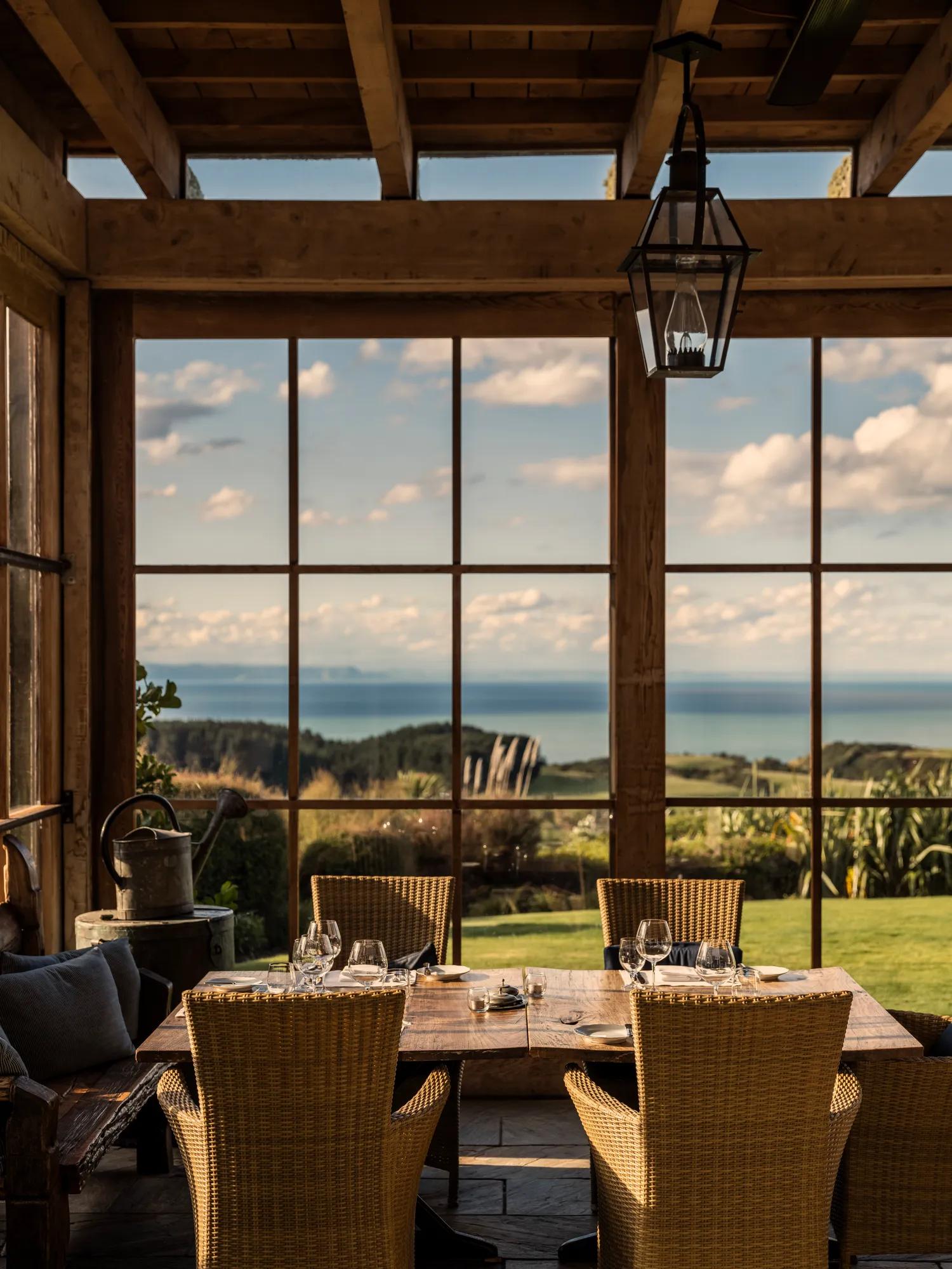 Dining table in a loggia with floor to ceiling windows and views of the Pacific Ocean