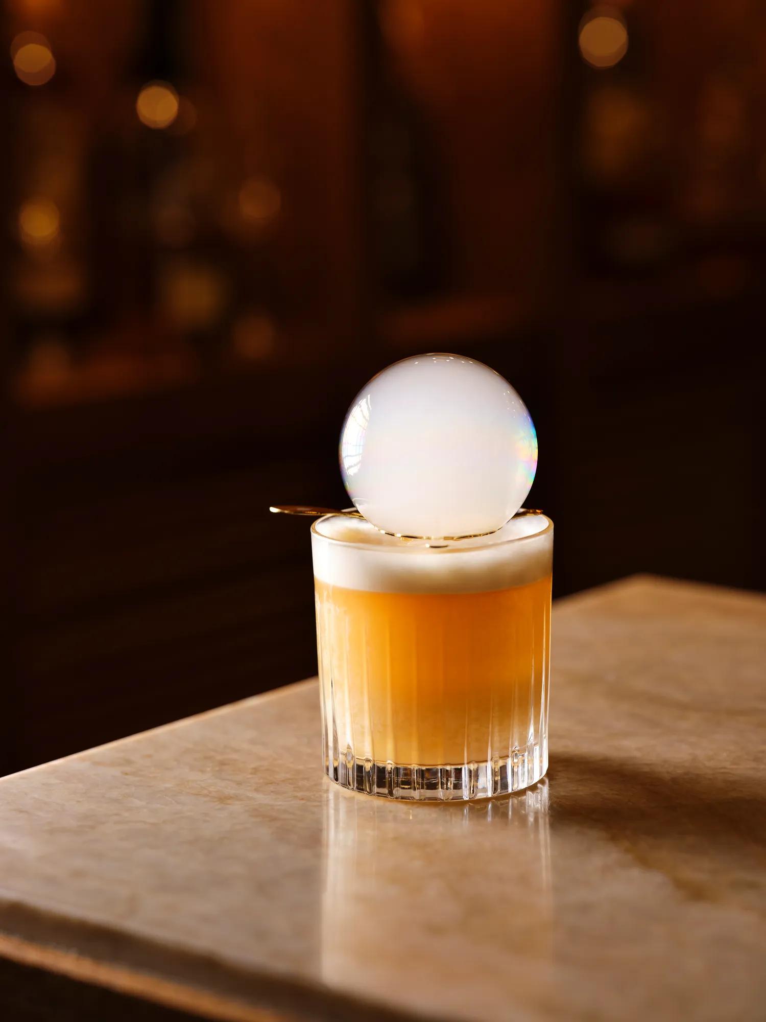 Smoke bubble resting on a beautifully presented whisky cocktail.