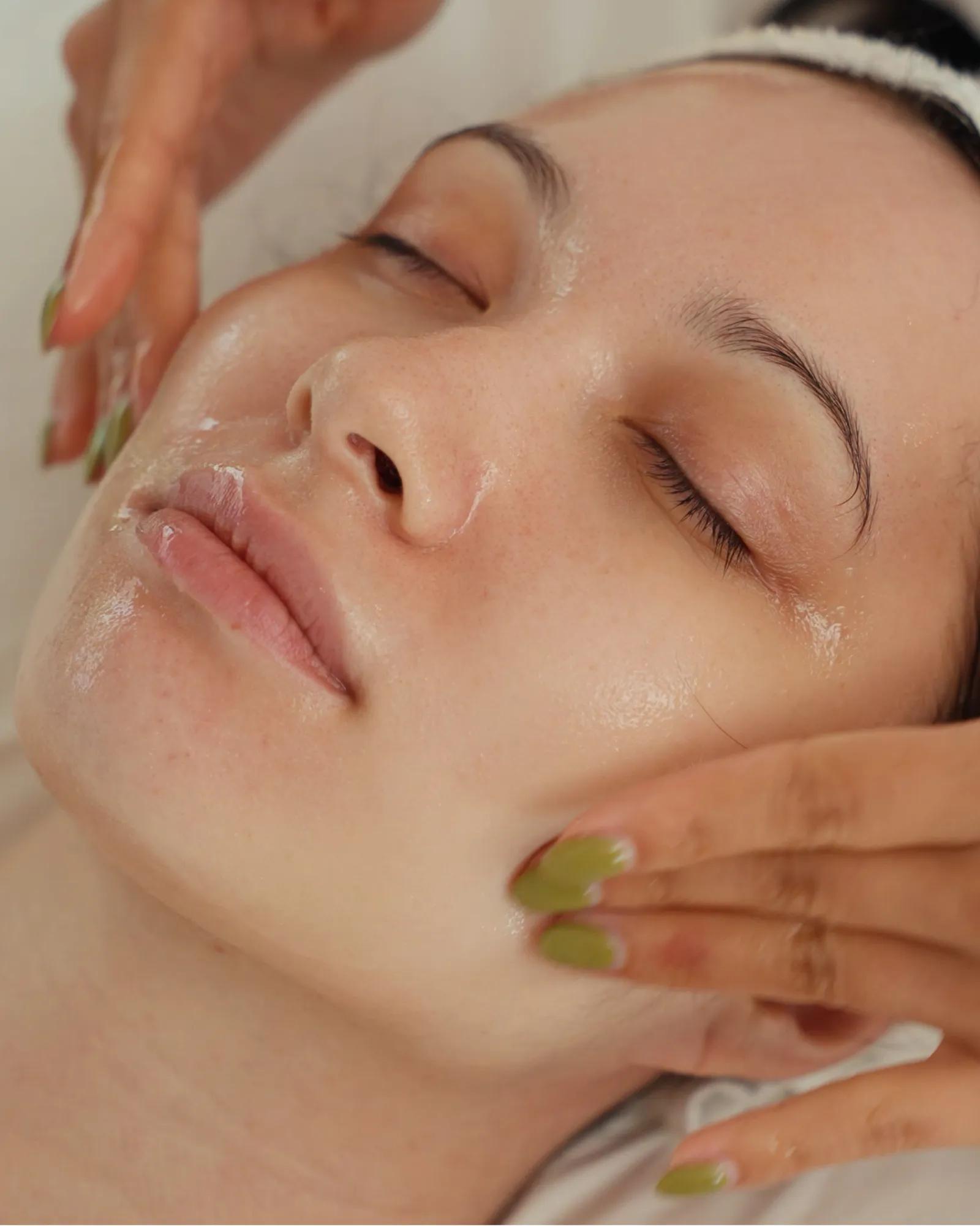 Close up shot of a woman’s face with her eyes closed and relaxed as she gets a facial at a luxury spa.