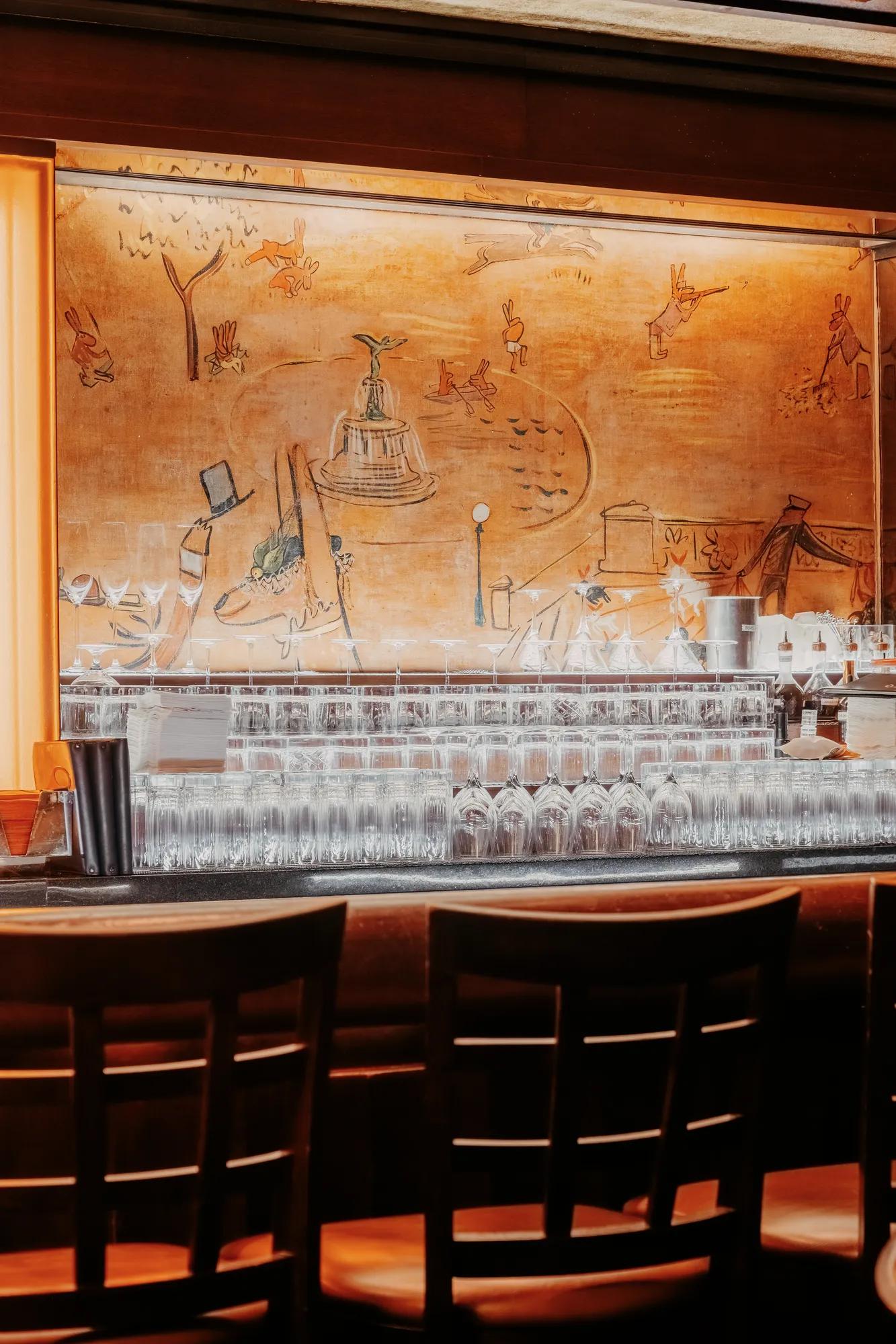 A golden room, with hand painted murals that depict new york city and central park. 