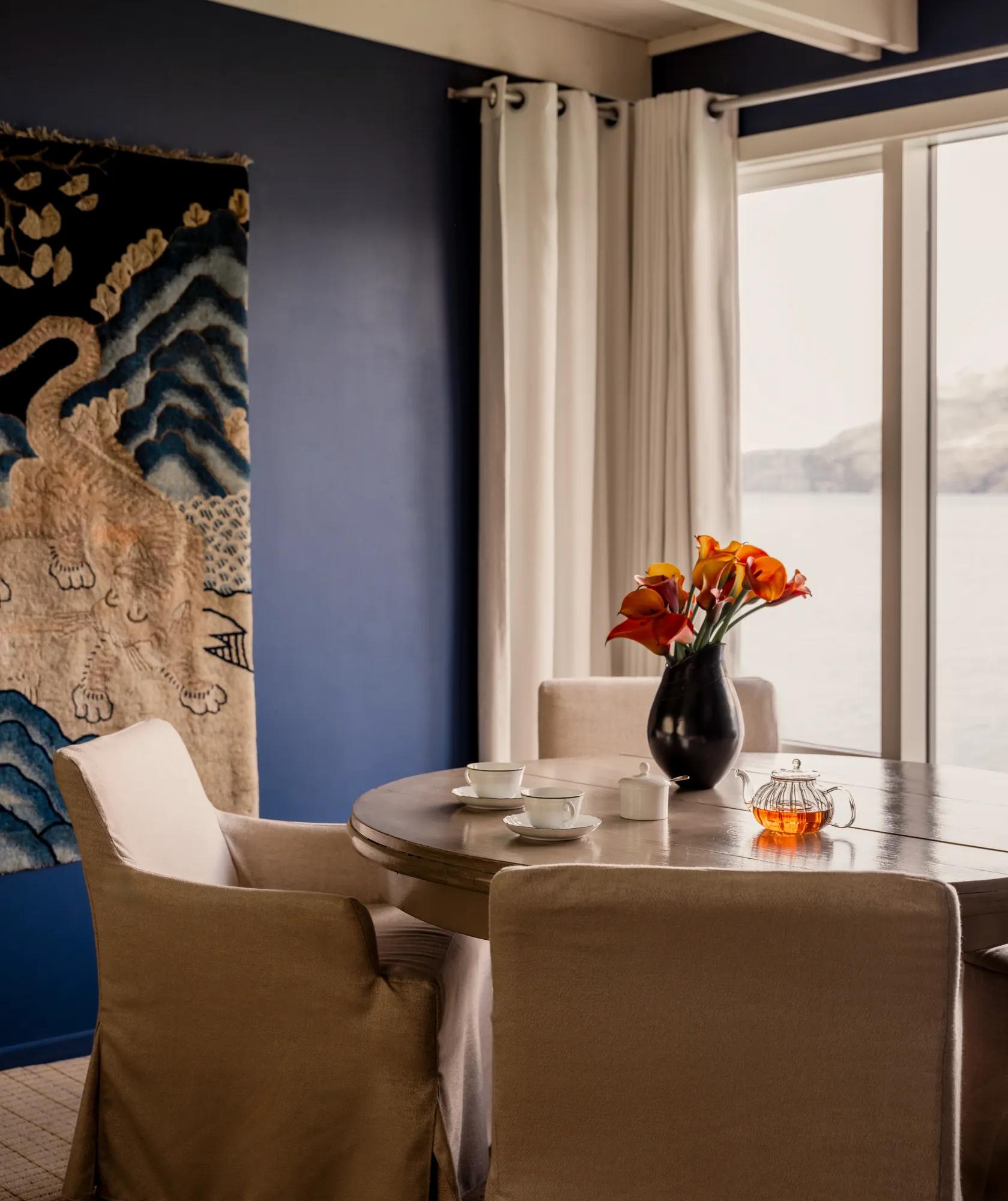 Dining table in the library at Rosewood Matakauri with a ancient tiger tapestry on the wall and lake and mountain views.