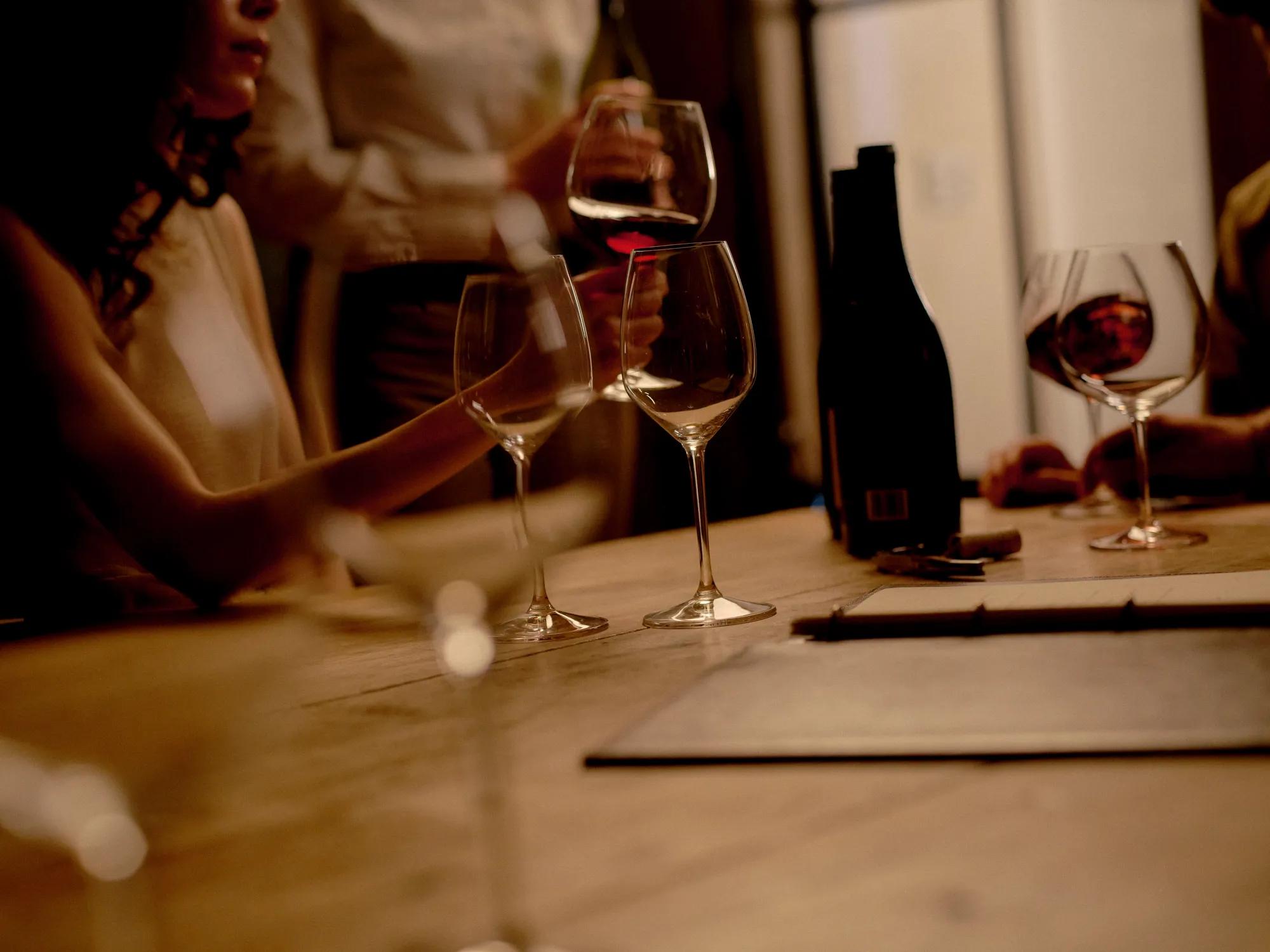 Man standing in a dimly lit barrel room holding a glass of wine