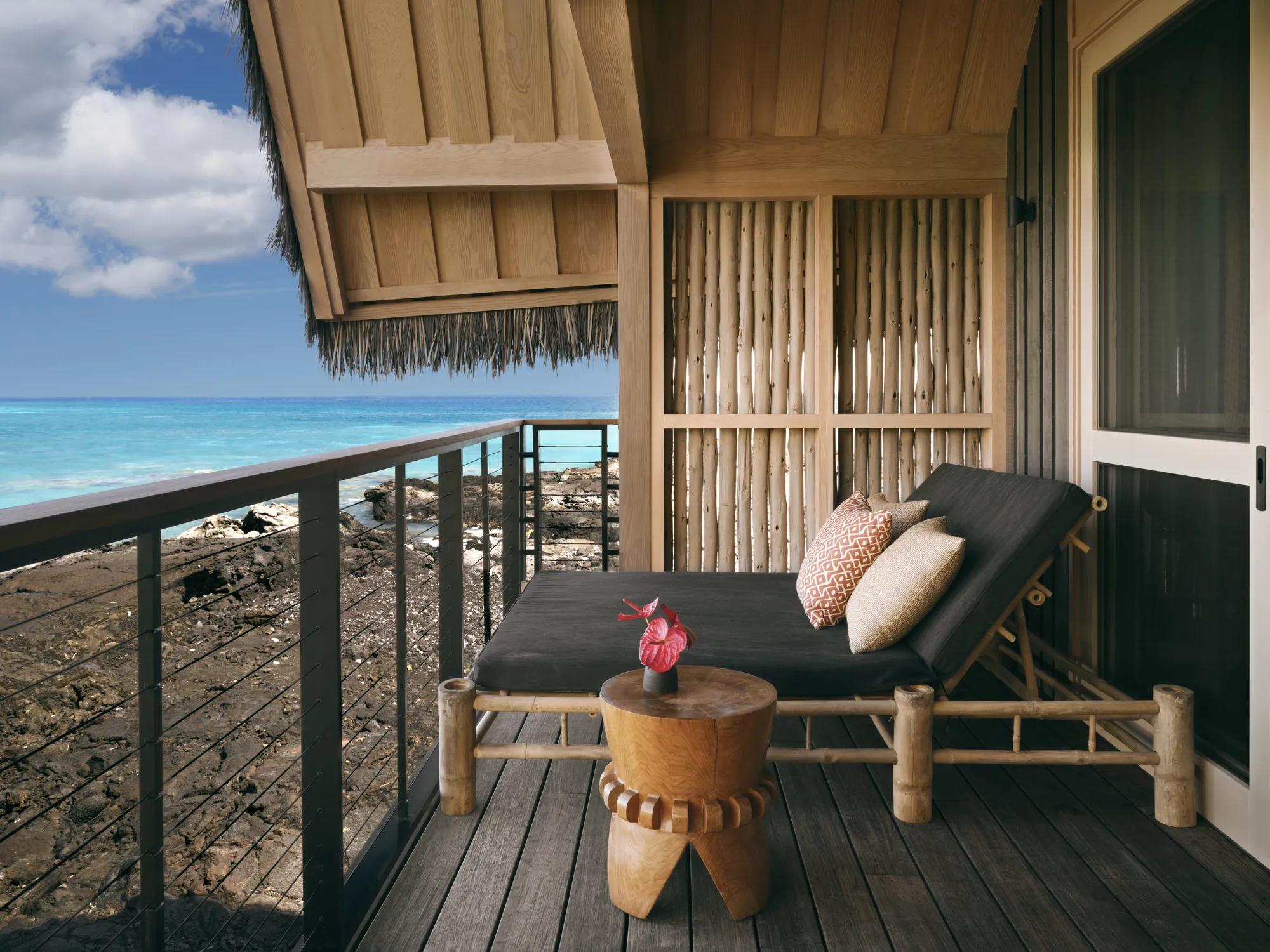 Lanai lounger overlooking ocean and black lava shoreline with the thatched hale roof lining the frame