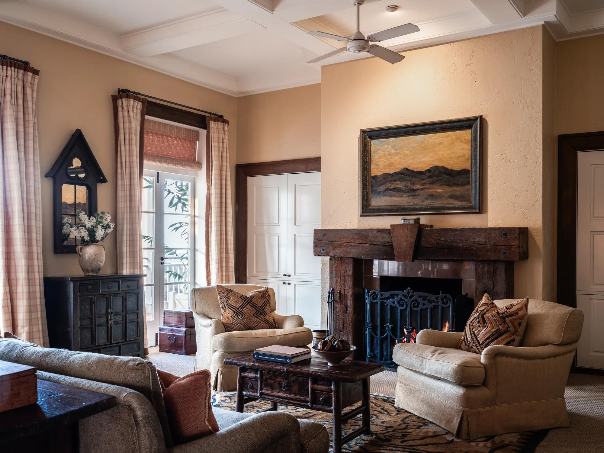 Cosy living space at Rosewood Kauri Cliffs with wood accents, comfortable seating and open fire. 