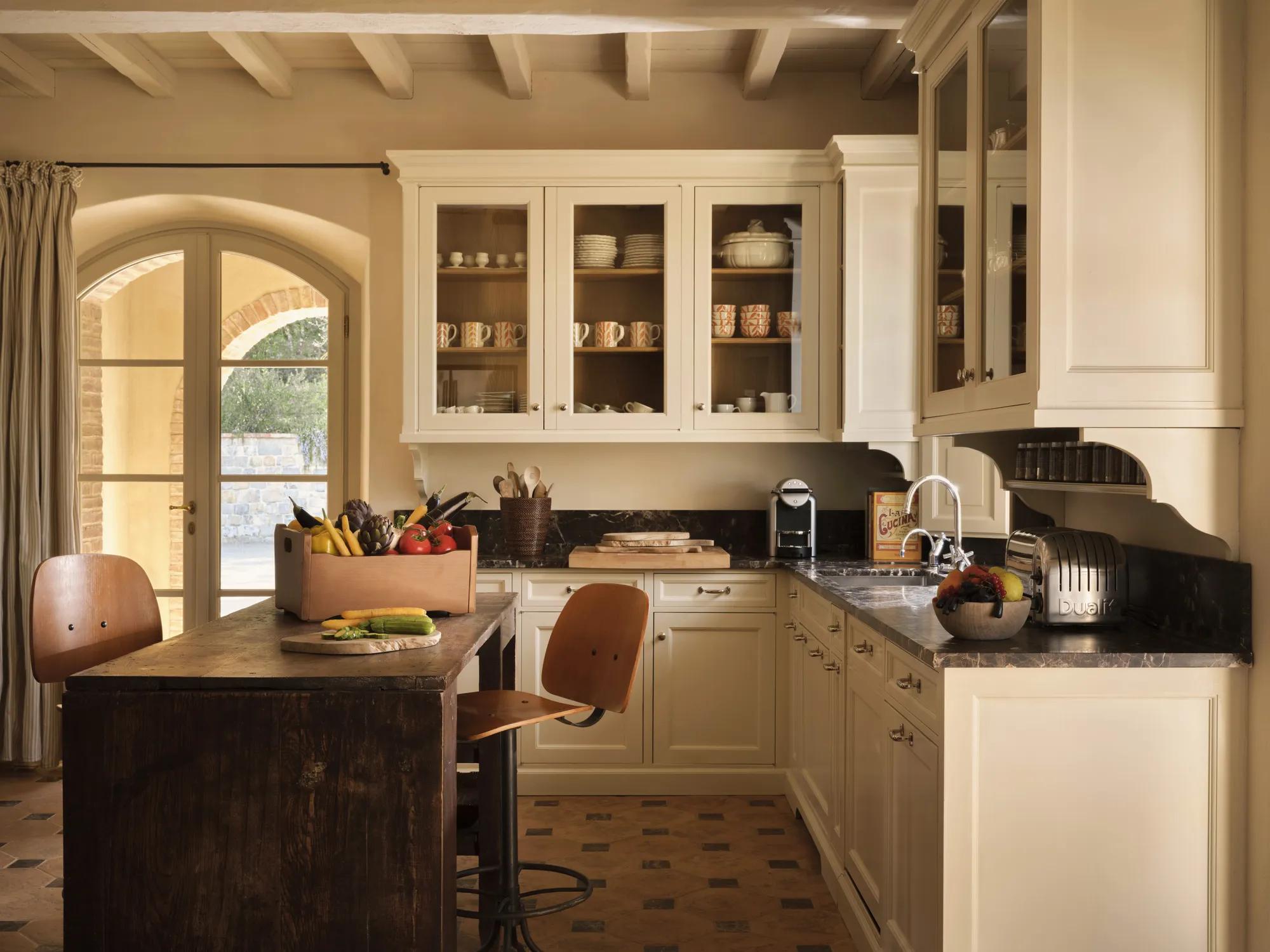 A man in a suit is pouring red wine from a  bottle into a glass.