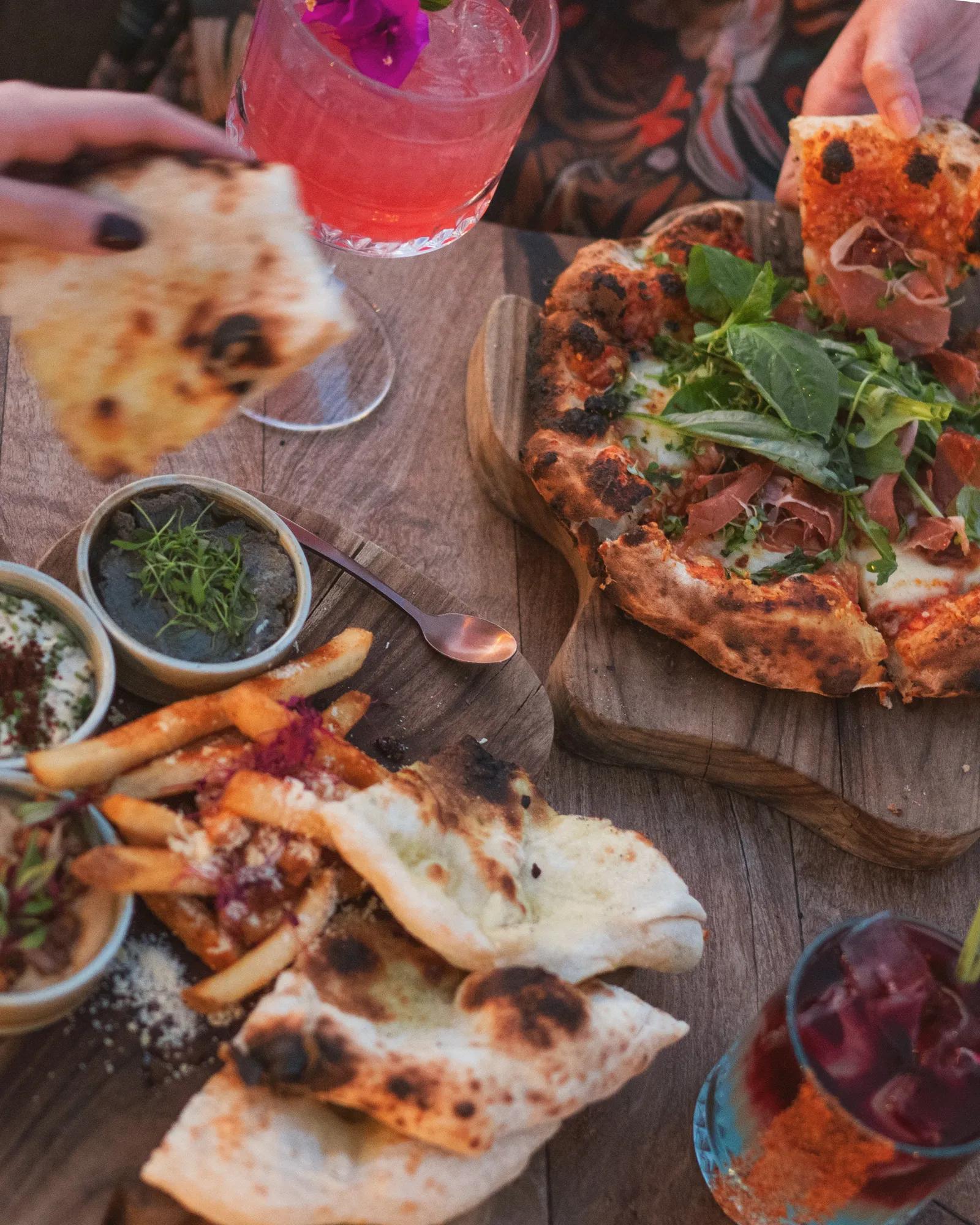 A colorful hot air balloon partially inflated and resting on the grass, with four people holding it steady under a clear sky in an open field.